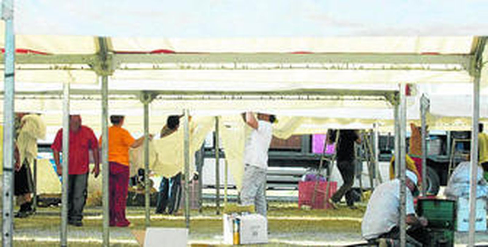 Un grupo de operarios coloca unos toldos en una de las instalaciones del ferial.