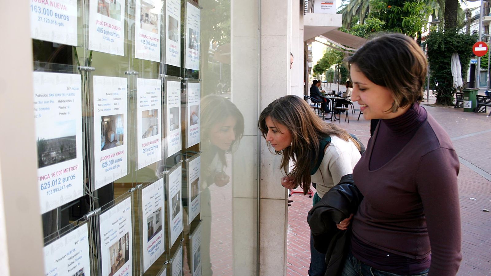 Dos jóvenes miran los anuncios de alquiler de una inmobiliaria.