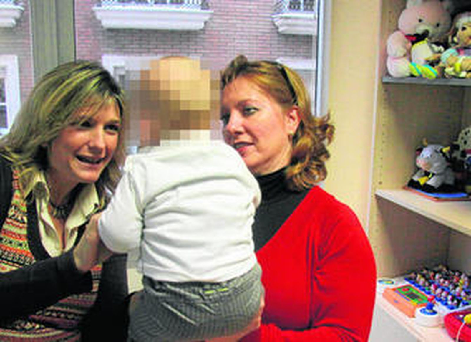 Ana María López (derecha), el bebé que ha acogido de urgencia y Marisa Alario, en la sede de Hogar Abierto.