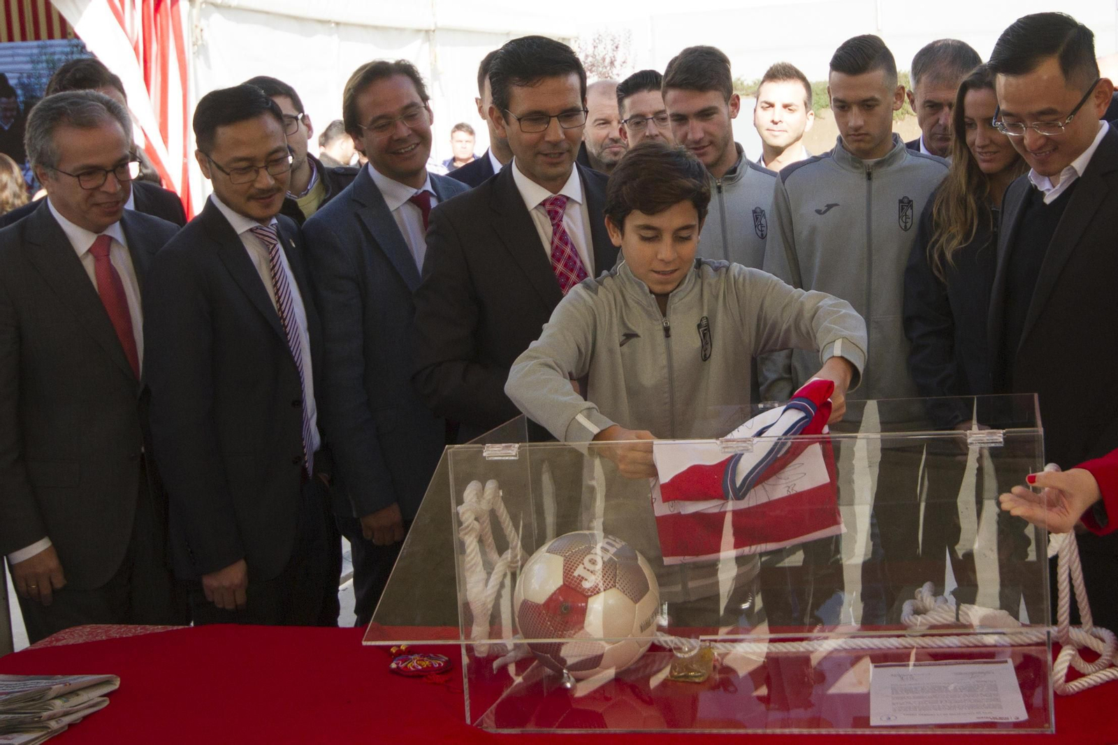 Un chaval de la cantera introduce un objeto en la urna del tiempo observado por la plana mayo del club y la ciudad.