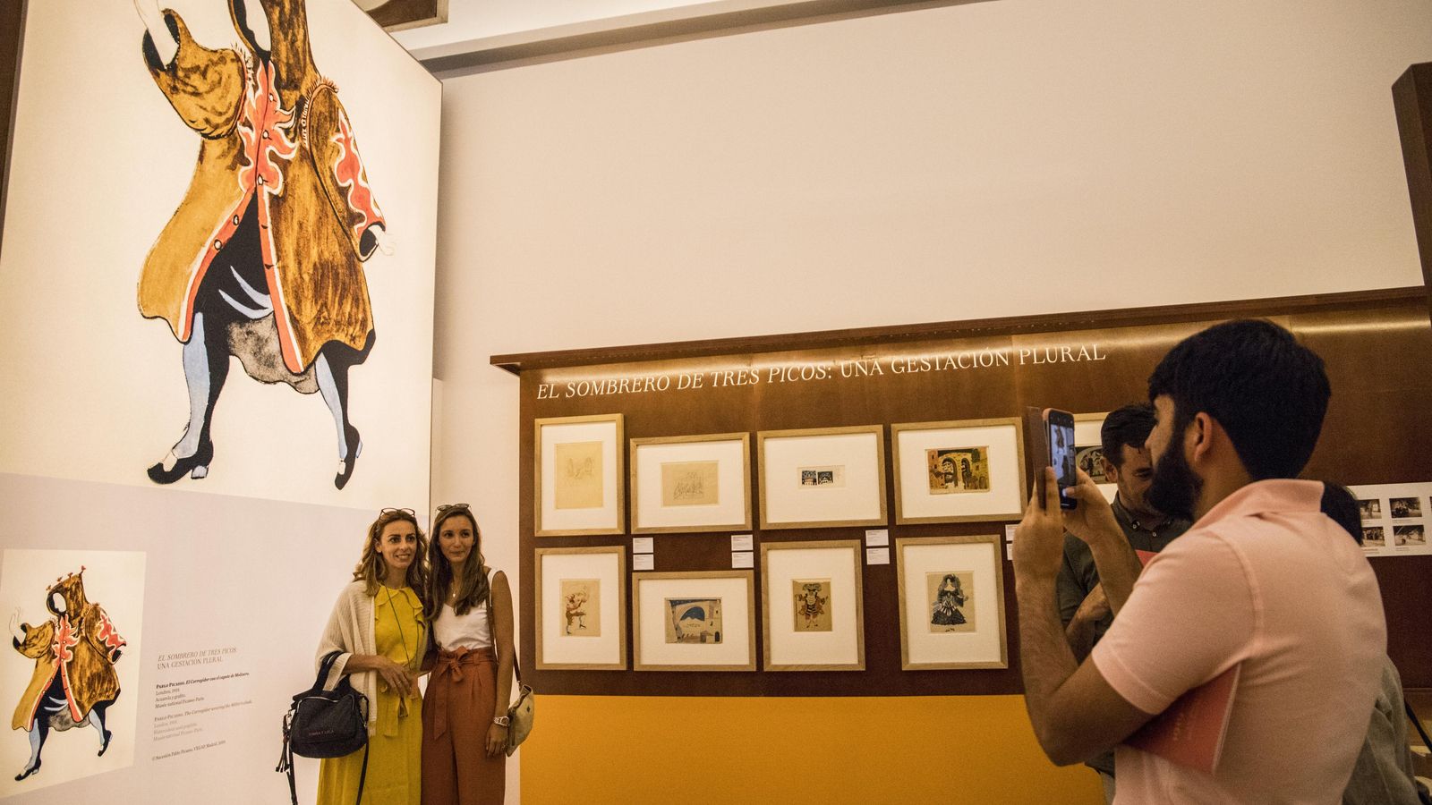 Dos asistentes a la muestra se fotografían junto a dibujos de Picasso