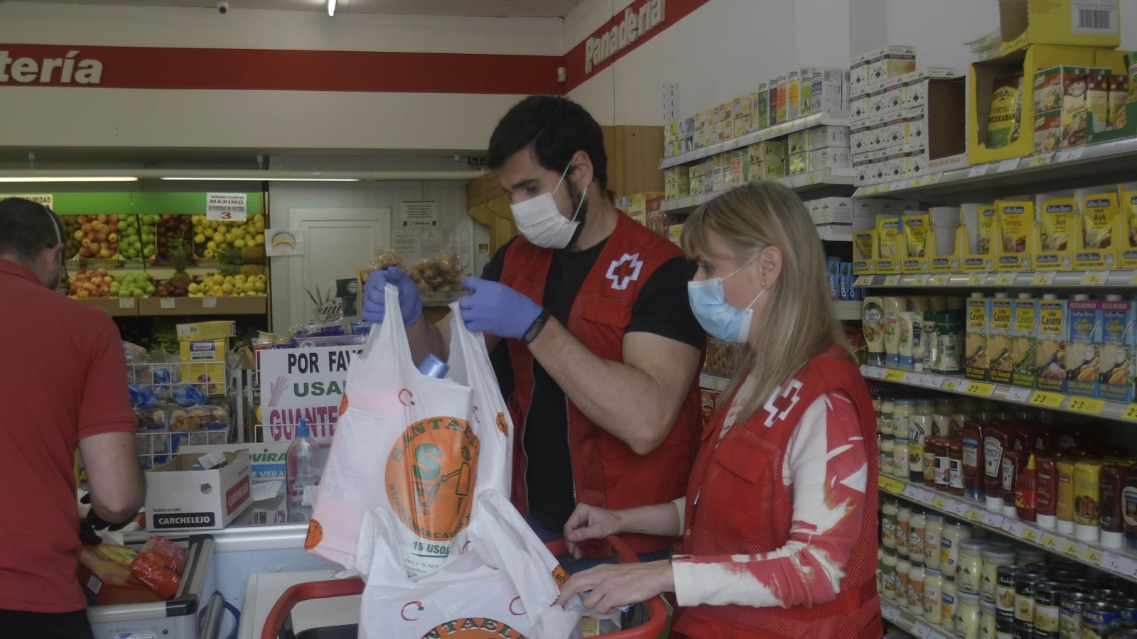 Dos personas de la Cruz Roja hacen la compra para las entregas a domicilio.