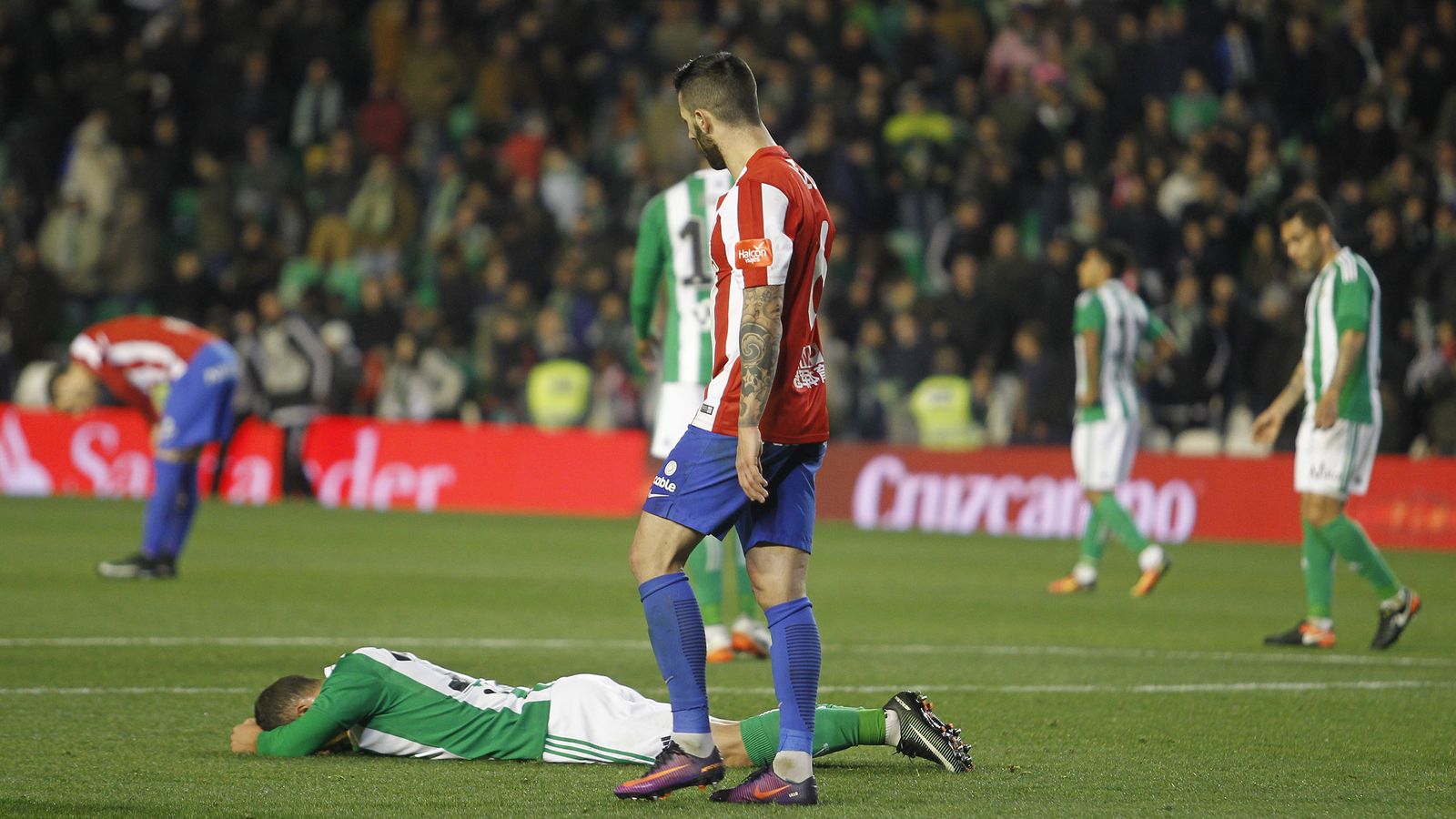 Un jugador bético se lamenta tumbado en el césped.