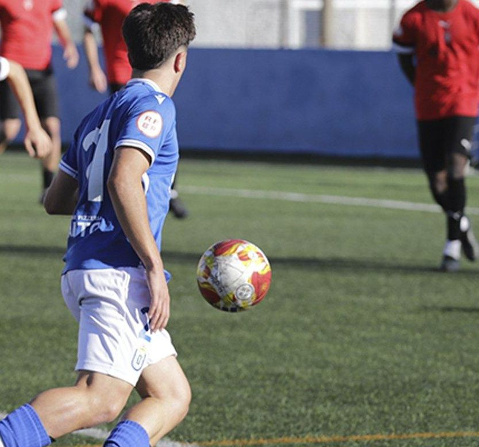 Un jugador del conjunto melillense conduce el balón ante la presión de varios futbolistas cañaeros.