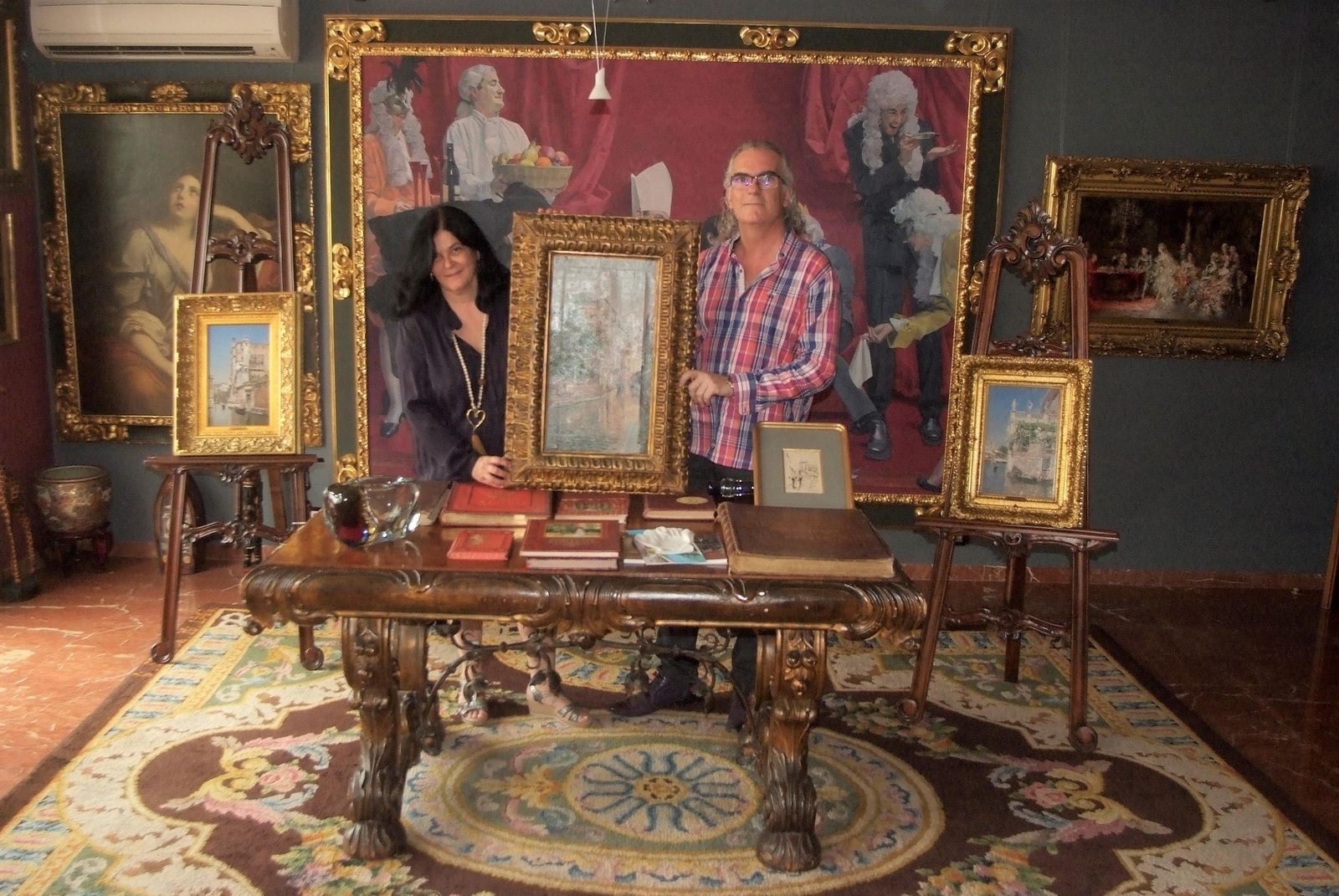 Carmen Muñoz y Manuel Vida en el salón de su casa, junto a tres de las obras sobre Venecia que se mostraran en el Espacio 2 del Museo de Arte de Almería.