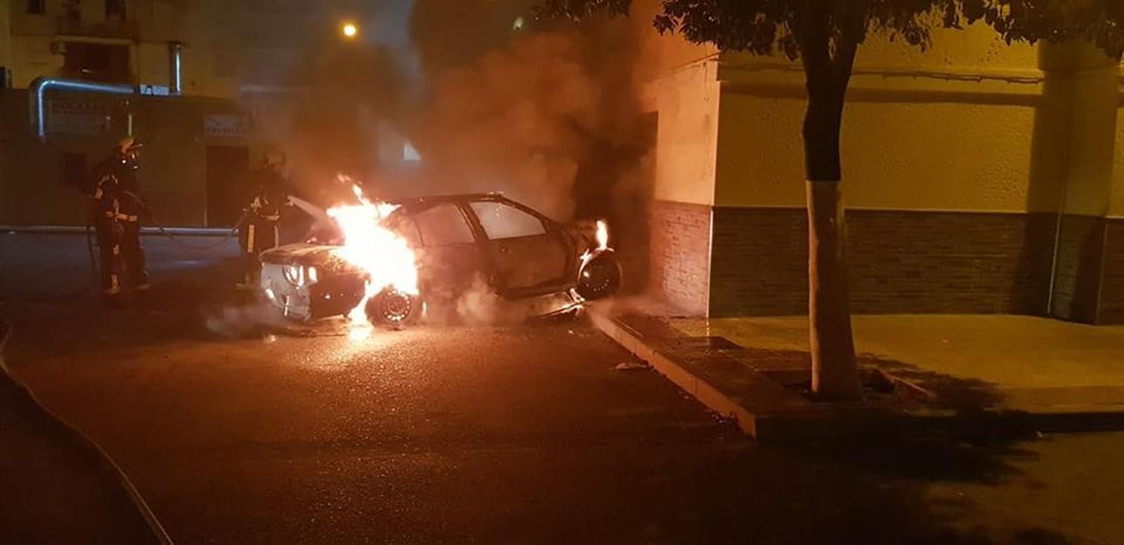 Lo bomberos sofocan el incendio de uno de los coches afectados.