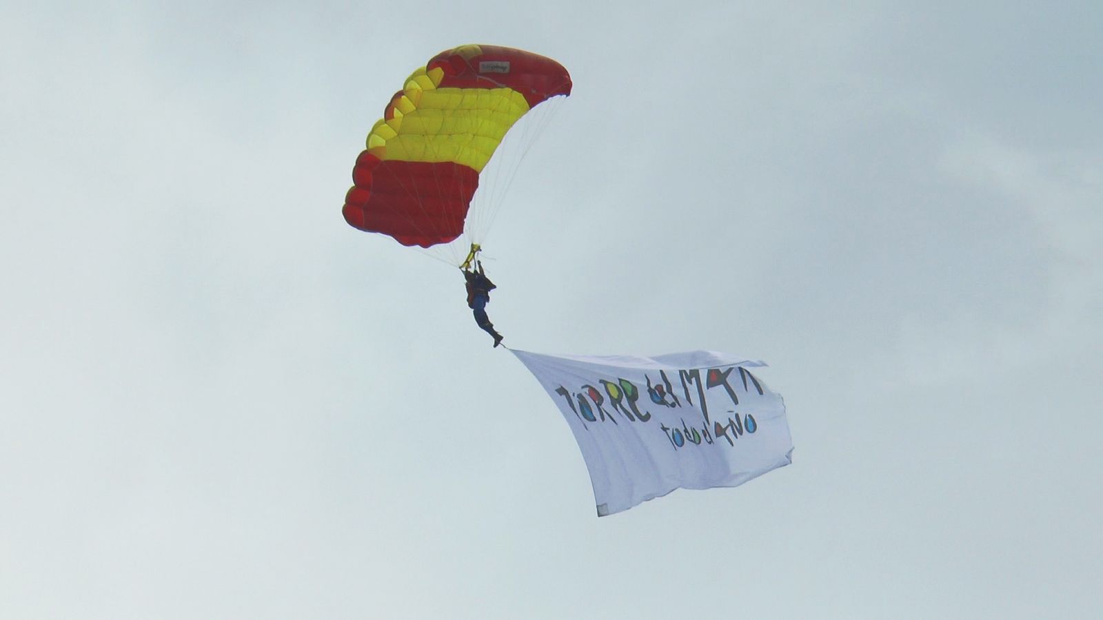 Un paracaidista porta una pancarta promocional del municipio malagueño.