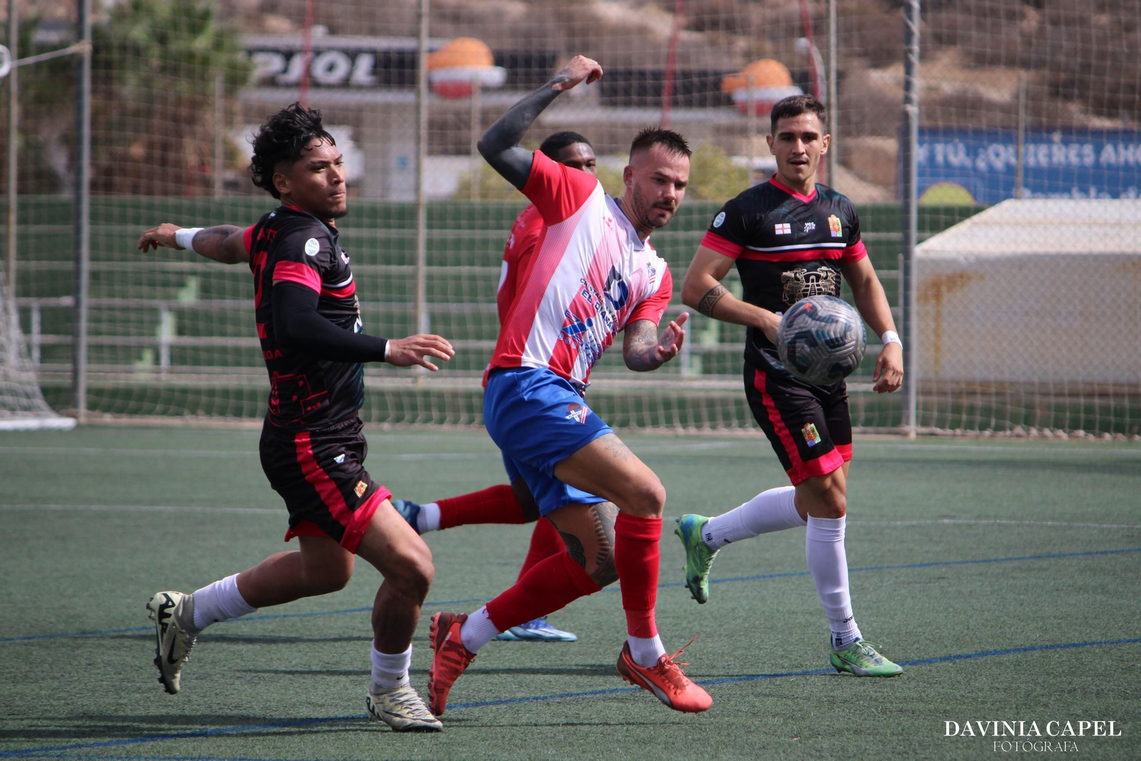 El rojiblanco Jay Spires disputa un balón con un rival durante el derbi almeriense entre el Poli Almería y el Cuevas.