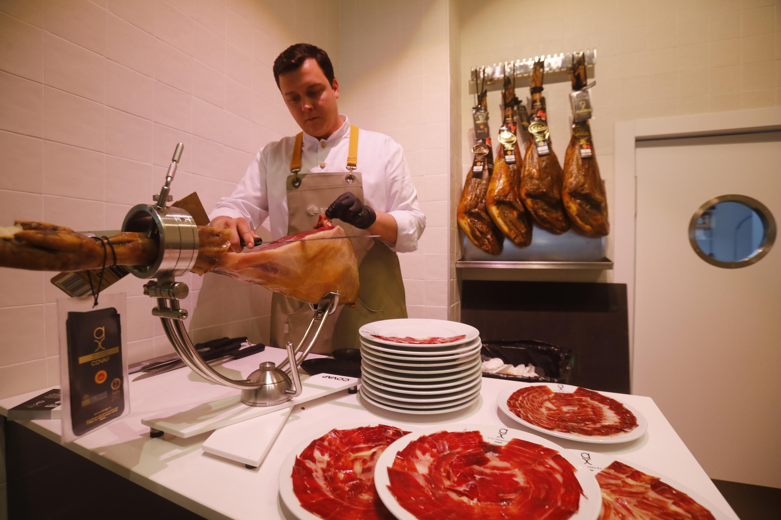 Un cortador prepara varios platos de jamón.