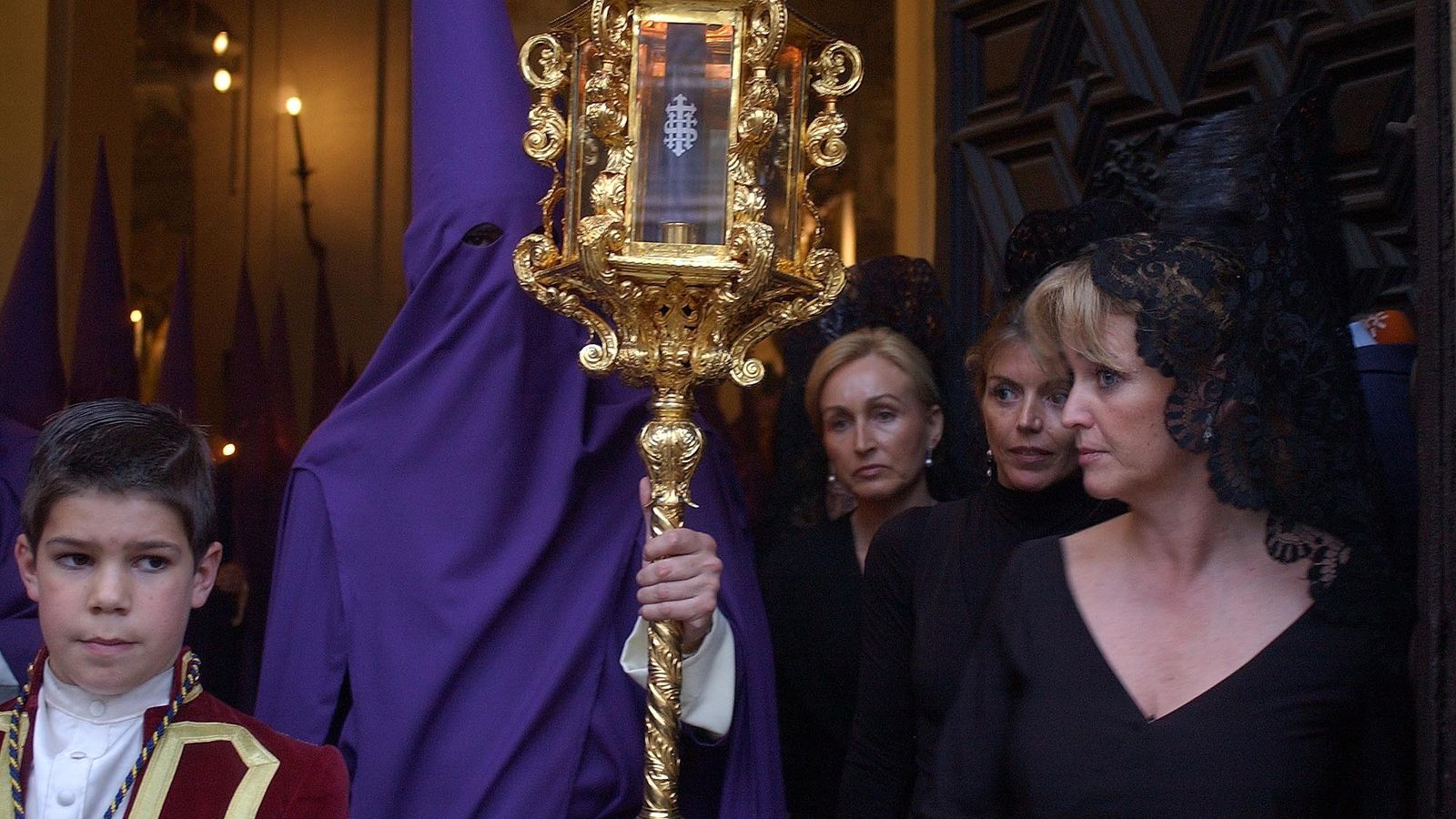 Mujeres vestidas de mantilla presencian la salida de la Quinta Angustia.