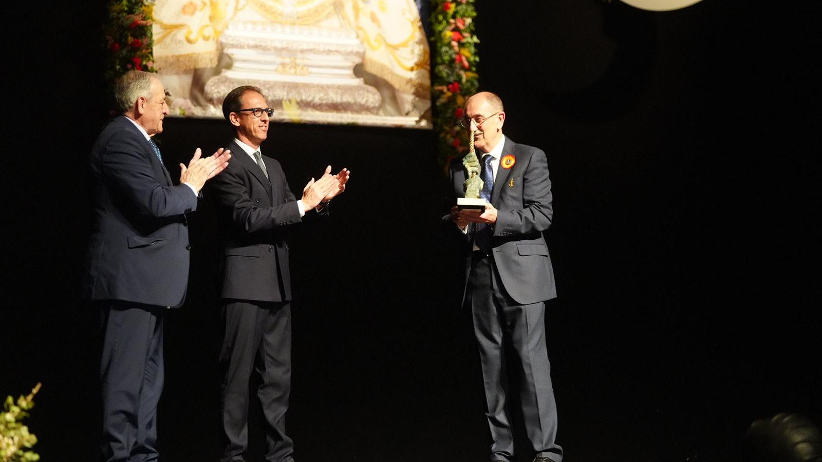 Escultura entregada al pregonero, Manuel Marín, con unas manos agarrando la bandera de la Virgen de Luna.