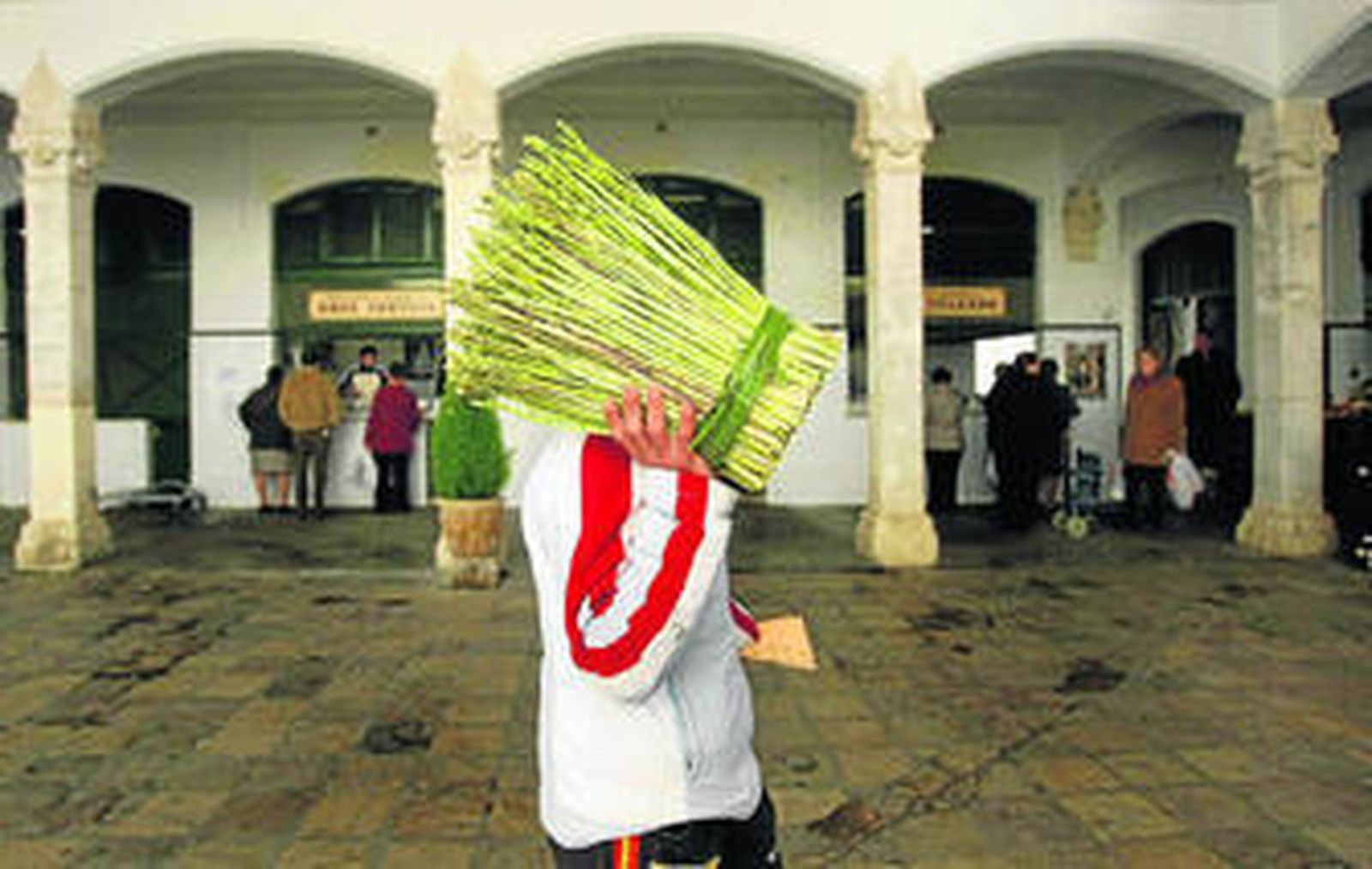 Un vendedor ambulante muestra una maceta de espárragos por el interior de la plaza de abastos asidonense.