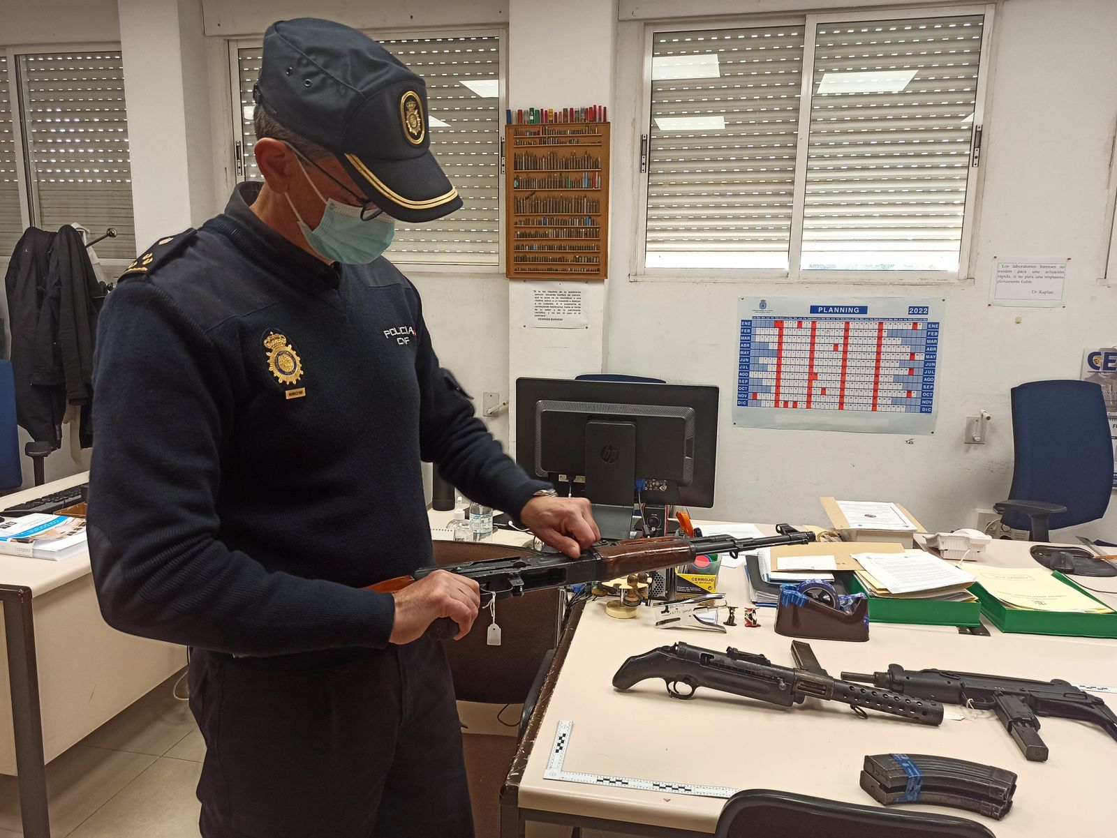 Un policía nacional manipula un arma de guerra intervenida en Sevilla.