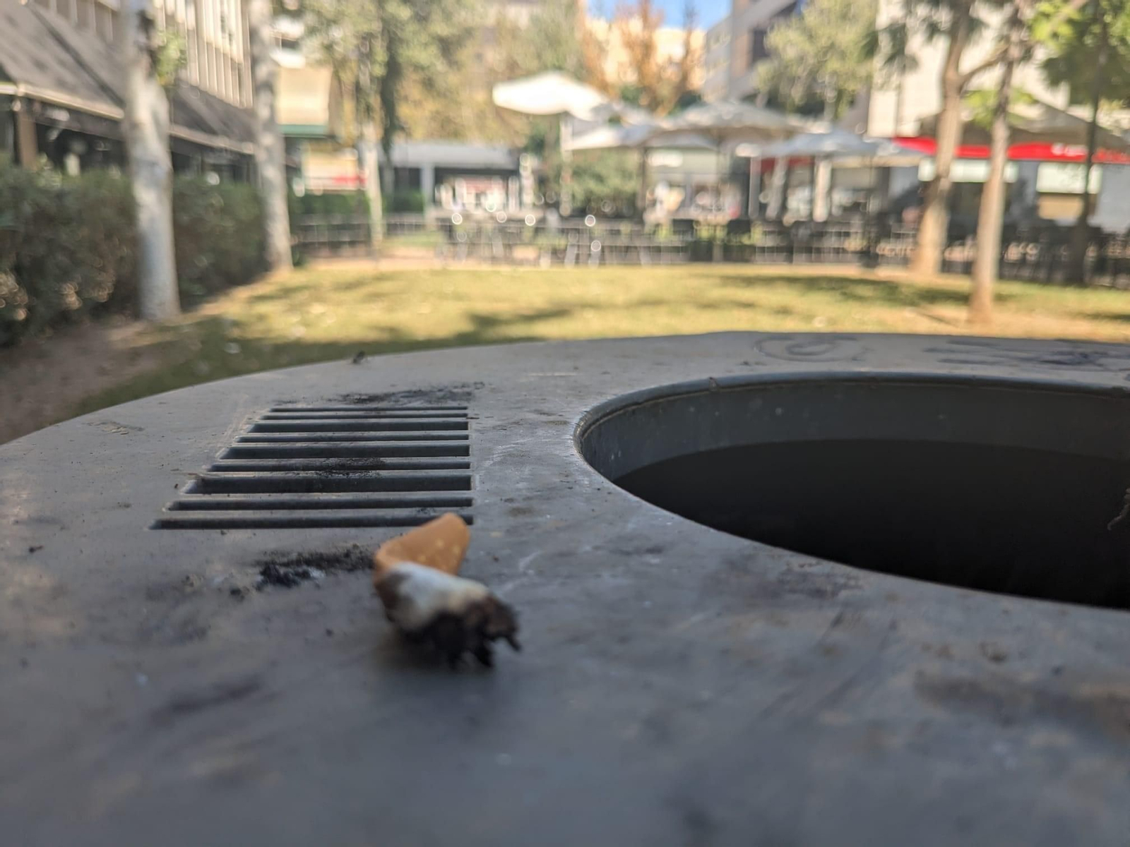 Papelera de metal con rejilla para los cigarros en el parque de Oliveros.