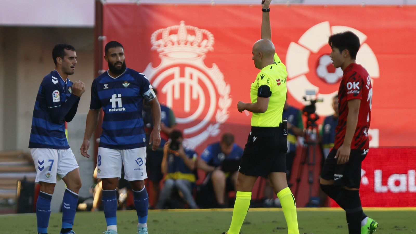 González Fuertes le muestra una tarjeta a Juanmi con Fekir como testigo.