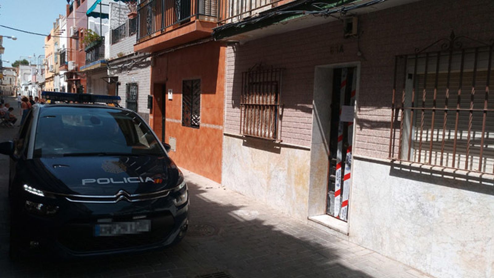 Un patrullero custodia la entrada al edificio, precintado por orden judicial.