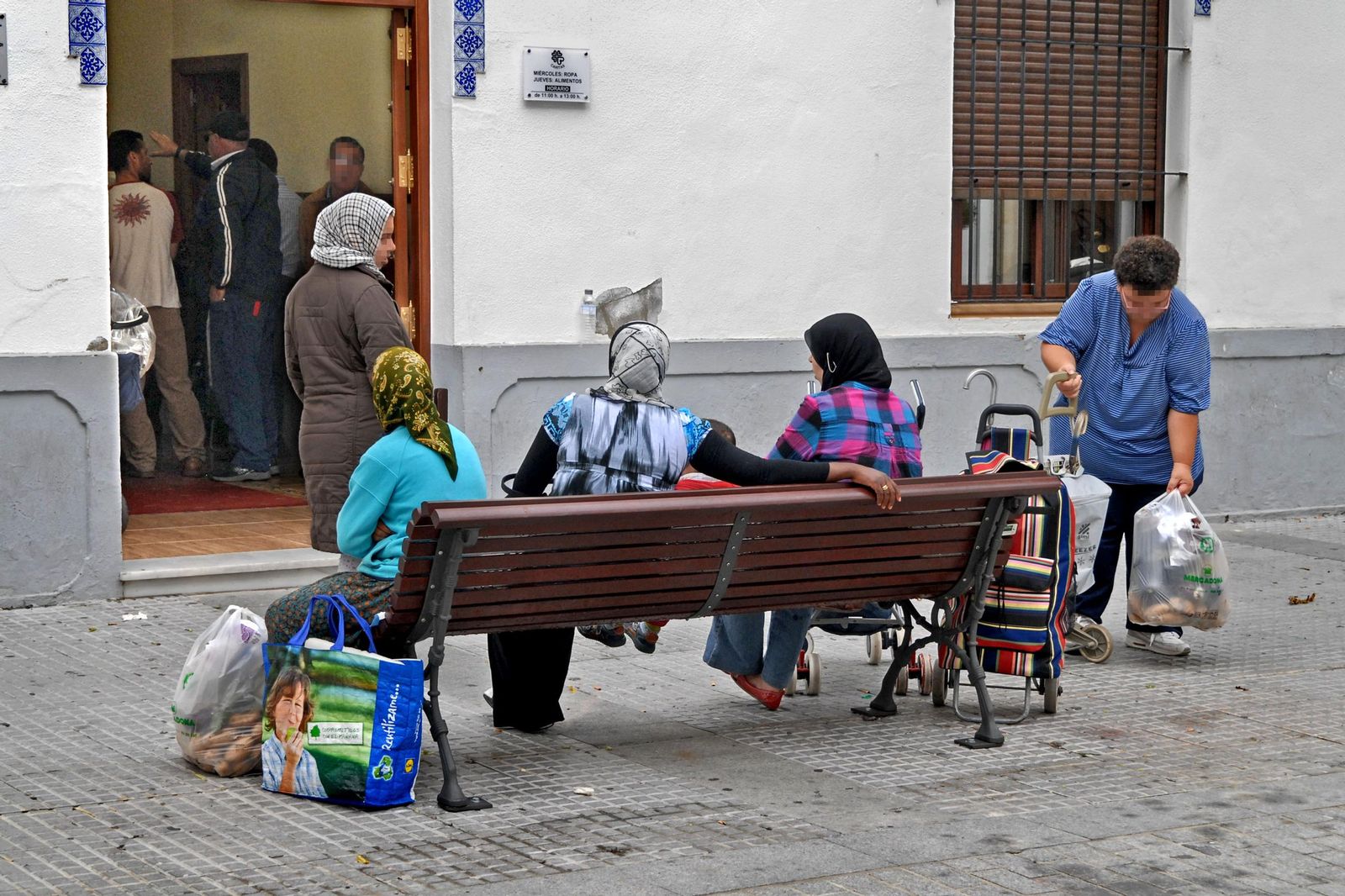 Mujeres hacen cola para recibir alimentos en Chiclana.