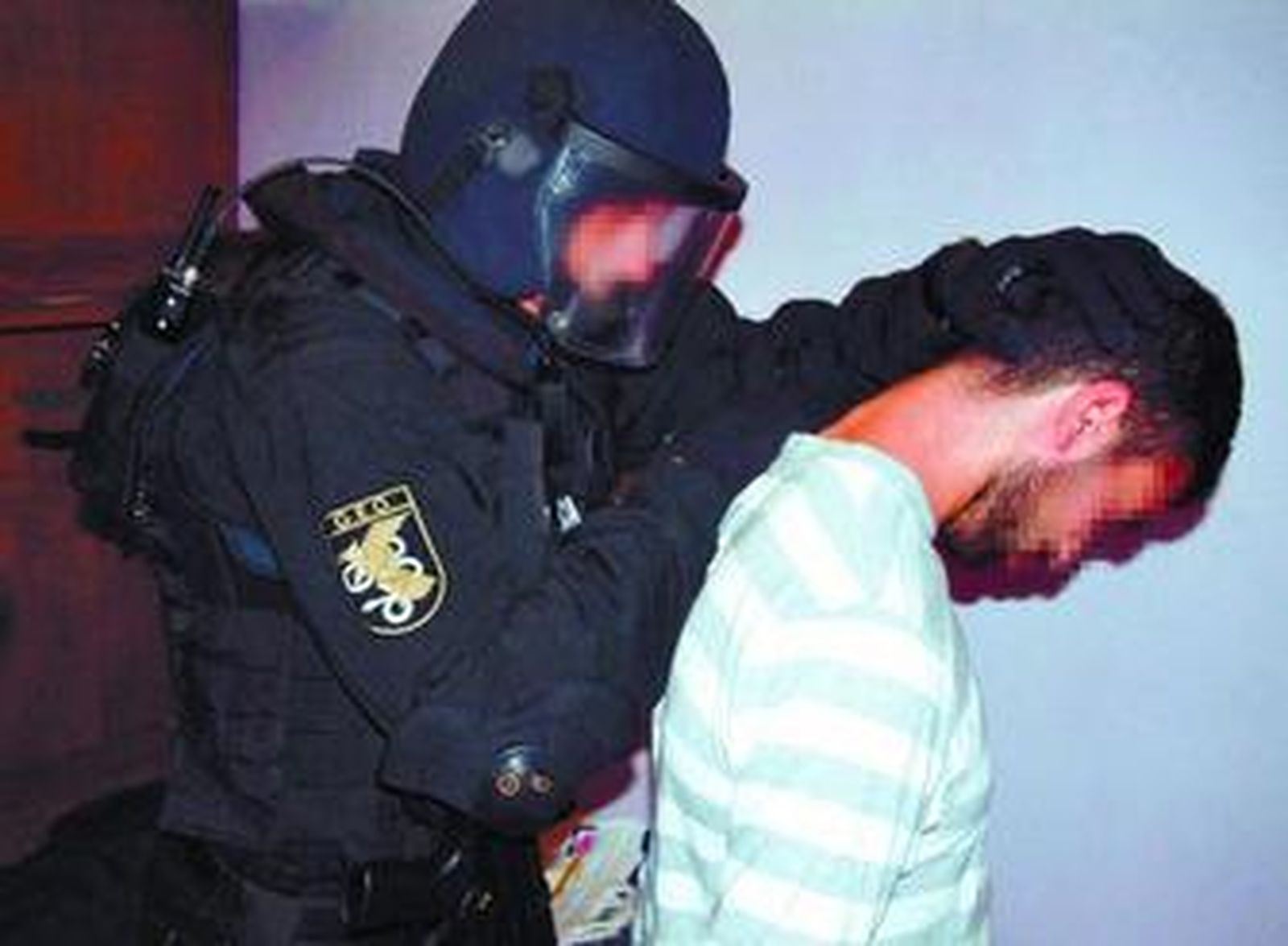 Un agente se lleva a uno de los supuestos islamistas detenidos la pasada semana en la operación Amat.