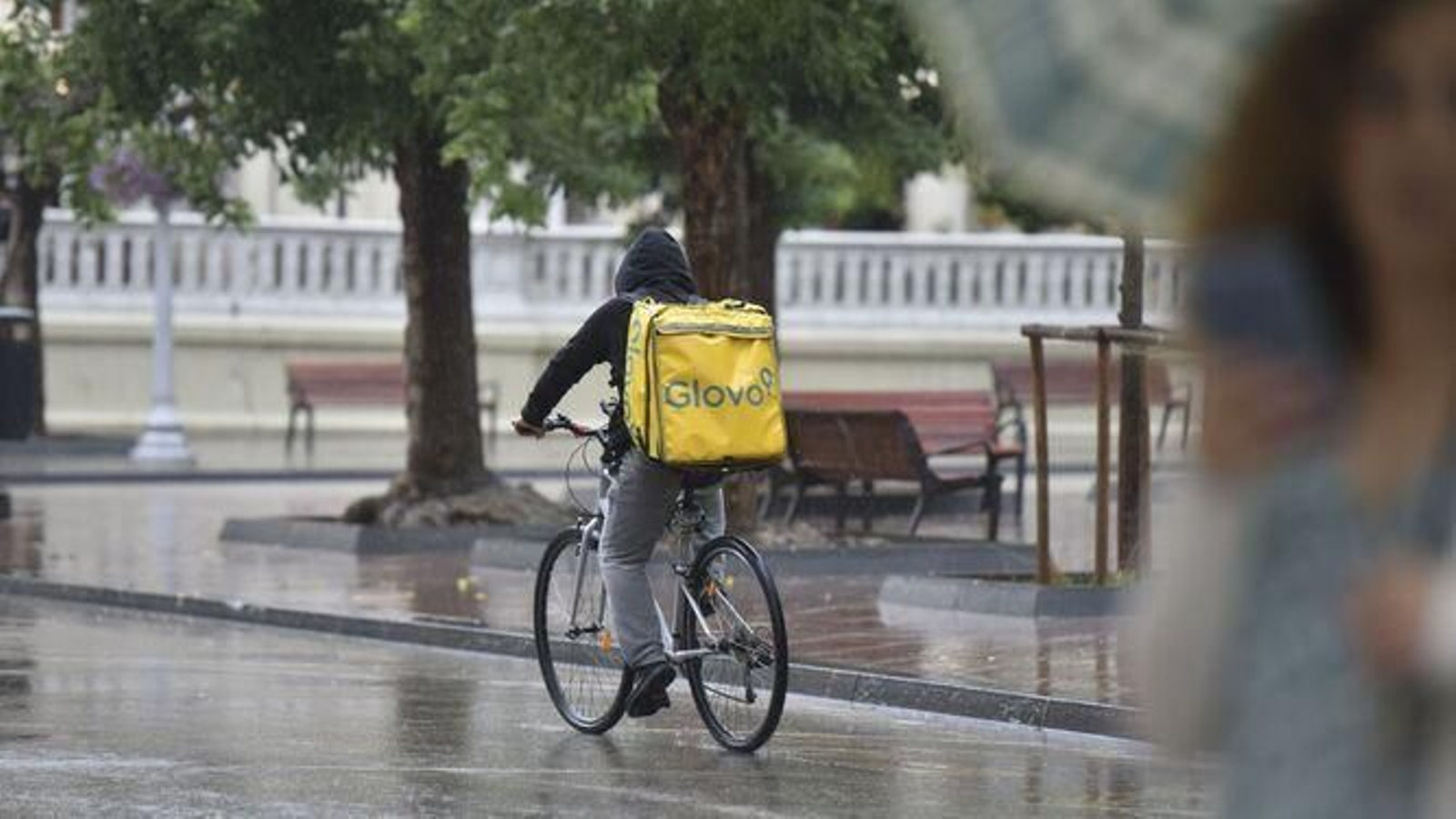 Un repartidor en bicicleta bajo la lluvia.