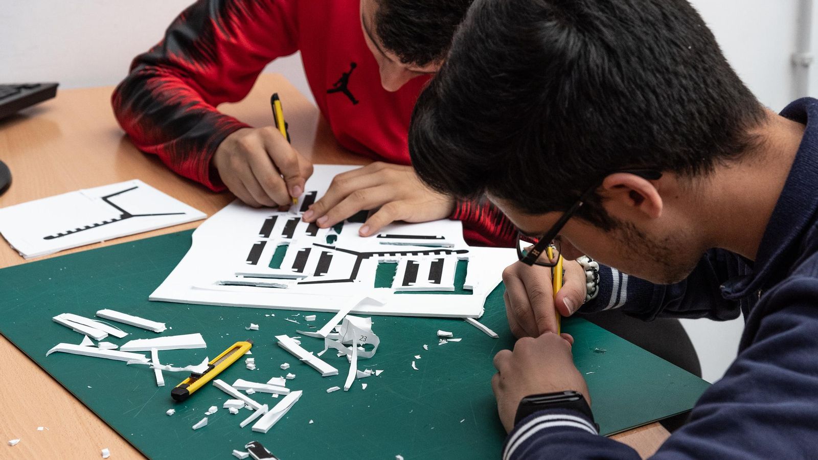 Alumnos recortan las piezas.