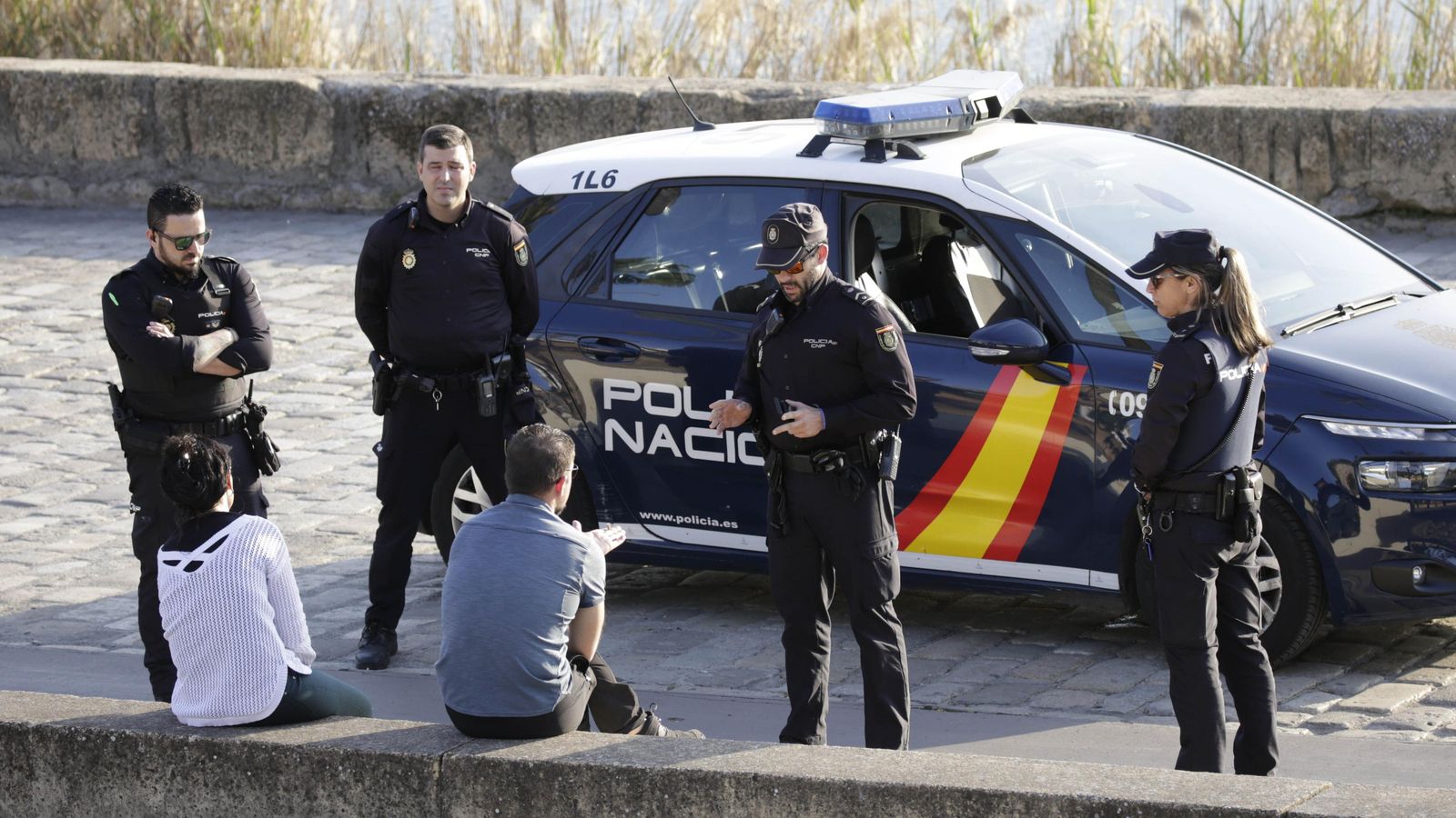 Policías nacionales explica a dos personas que no pueden pasear junto al río, el primer día de la cuarentena.