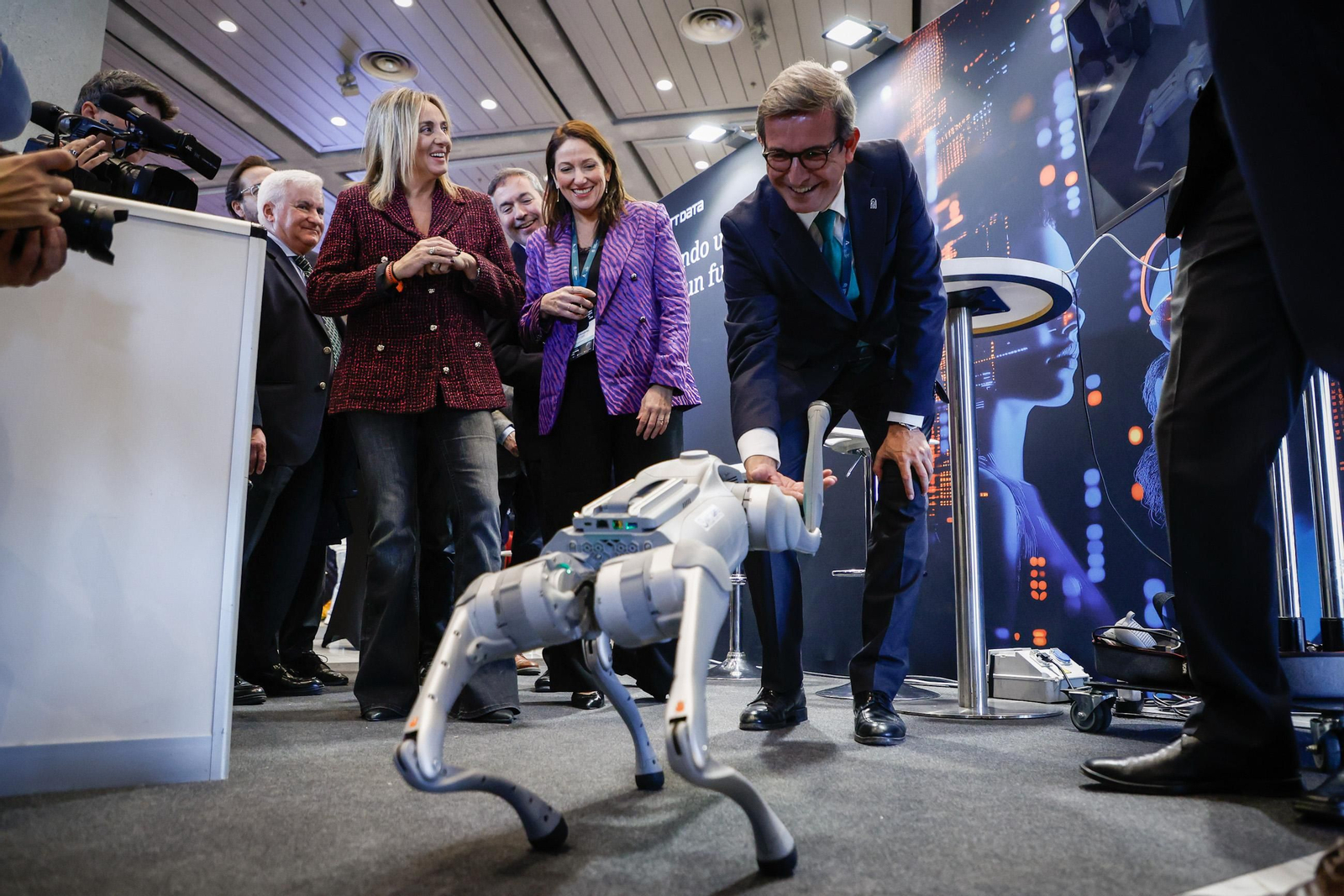 El consejero de Industria, Energía y Minas, Jorge Paradela, juega con un perro-robot, junto a la alcaldesa de Granada, Marifrán Carazo