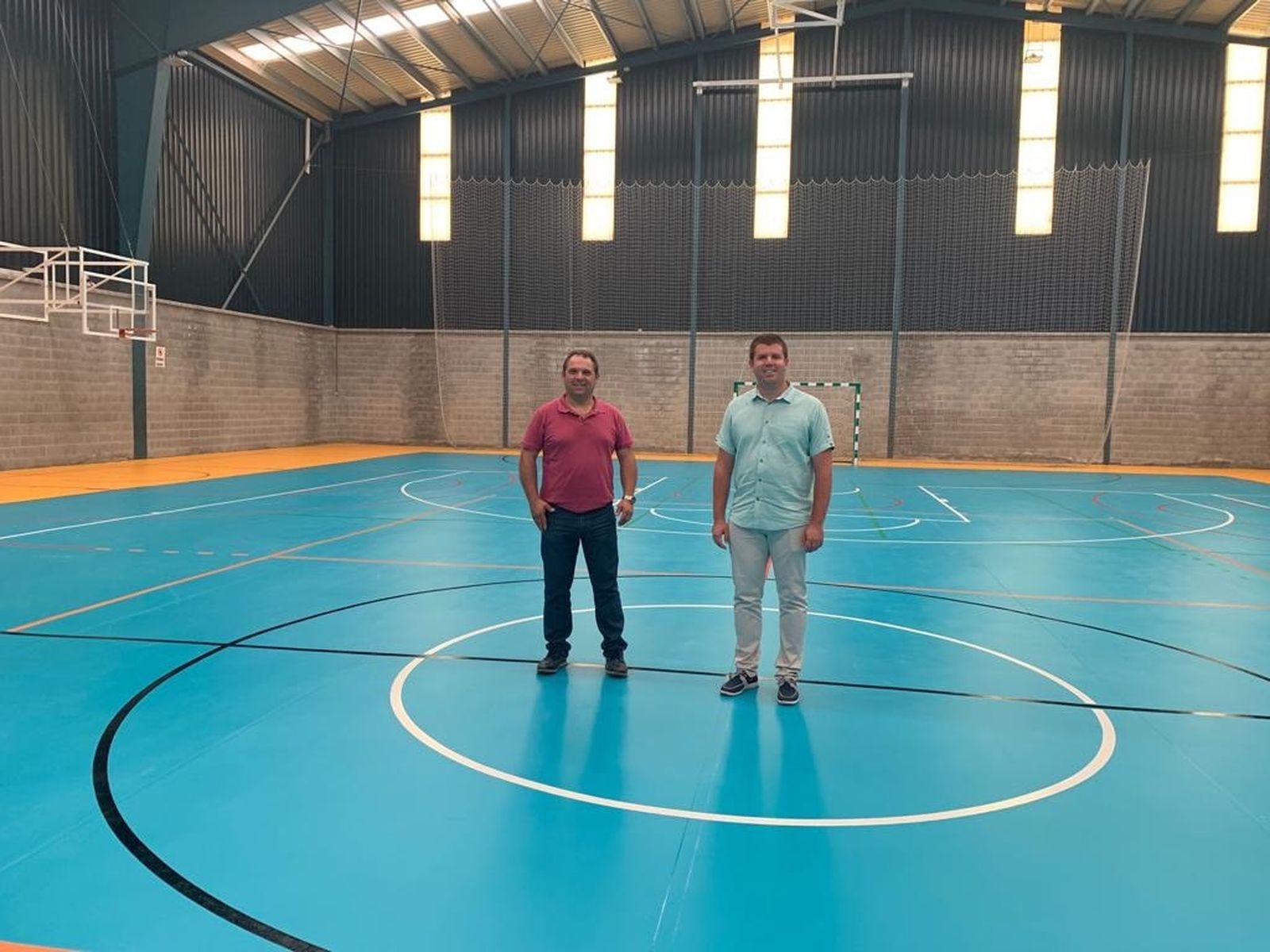 El alcalde y el concejal de Deportes de Monachil mostrando el nuevo suelo del pabellón cubierto