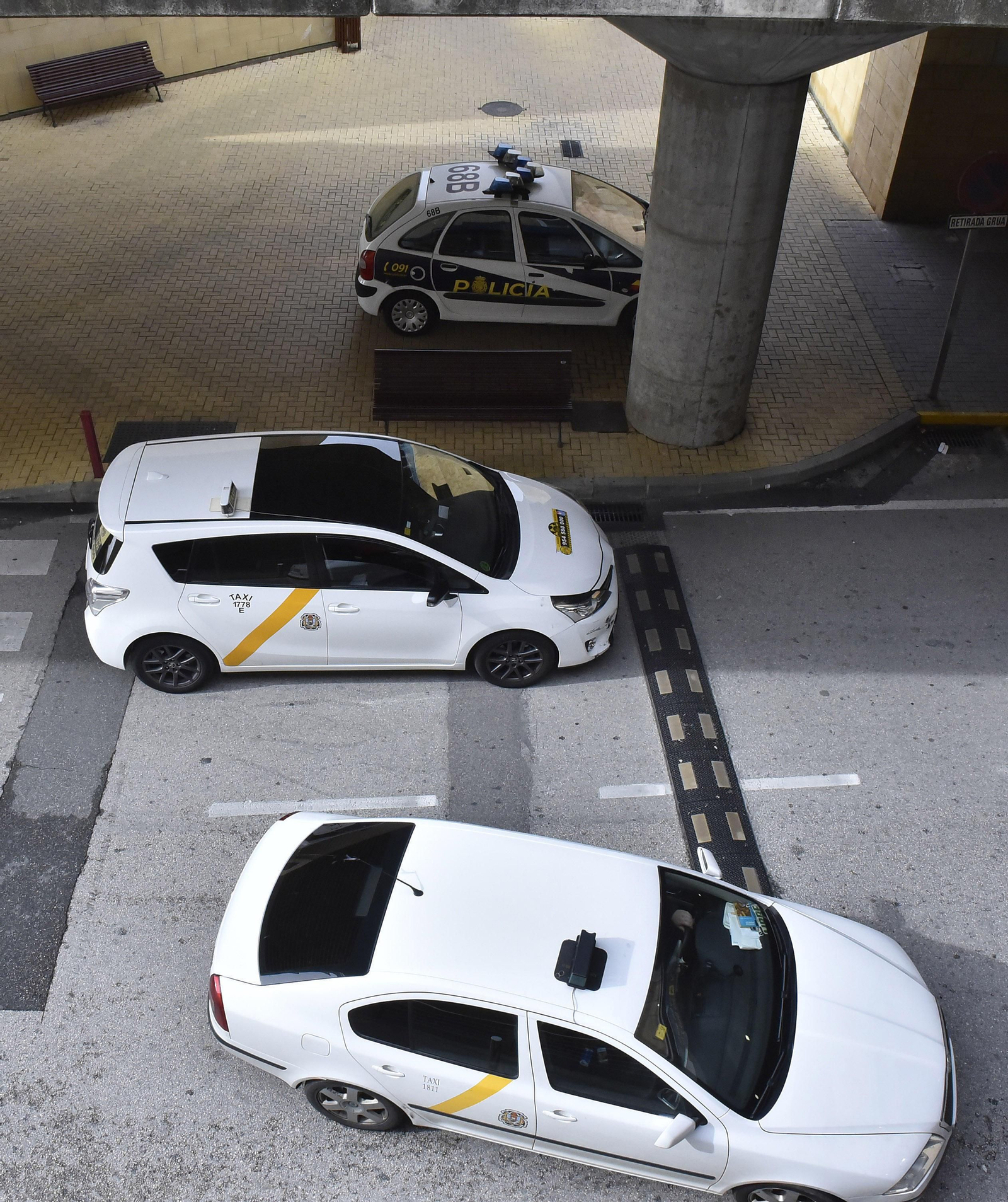 Un patrullero de la Policía Nacional junto a dos taxis en el aeropuerto.