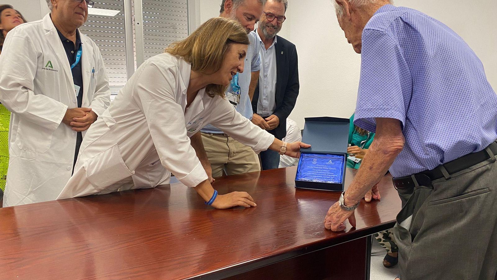 Médicos entregándole la placa a Pedro