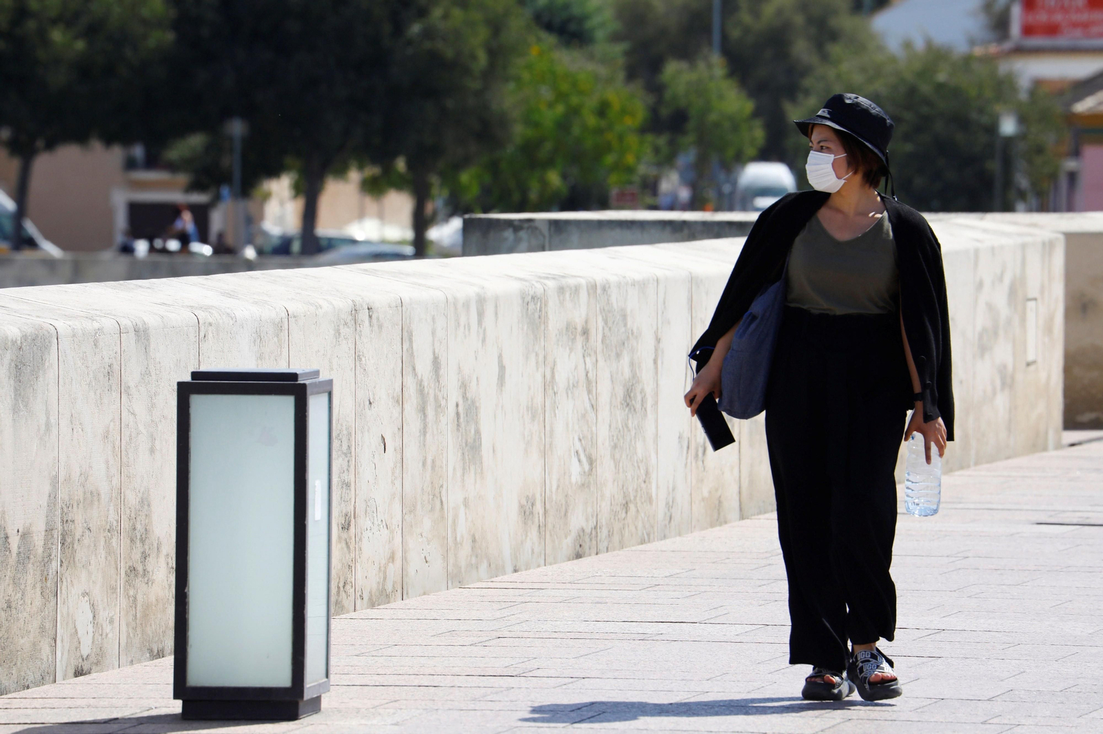 Una mujer pasea con mascarilla por el Puente Romano de Córdoba.