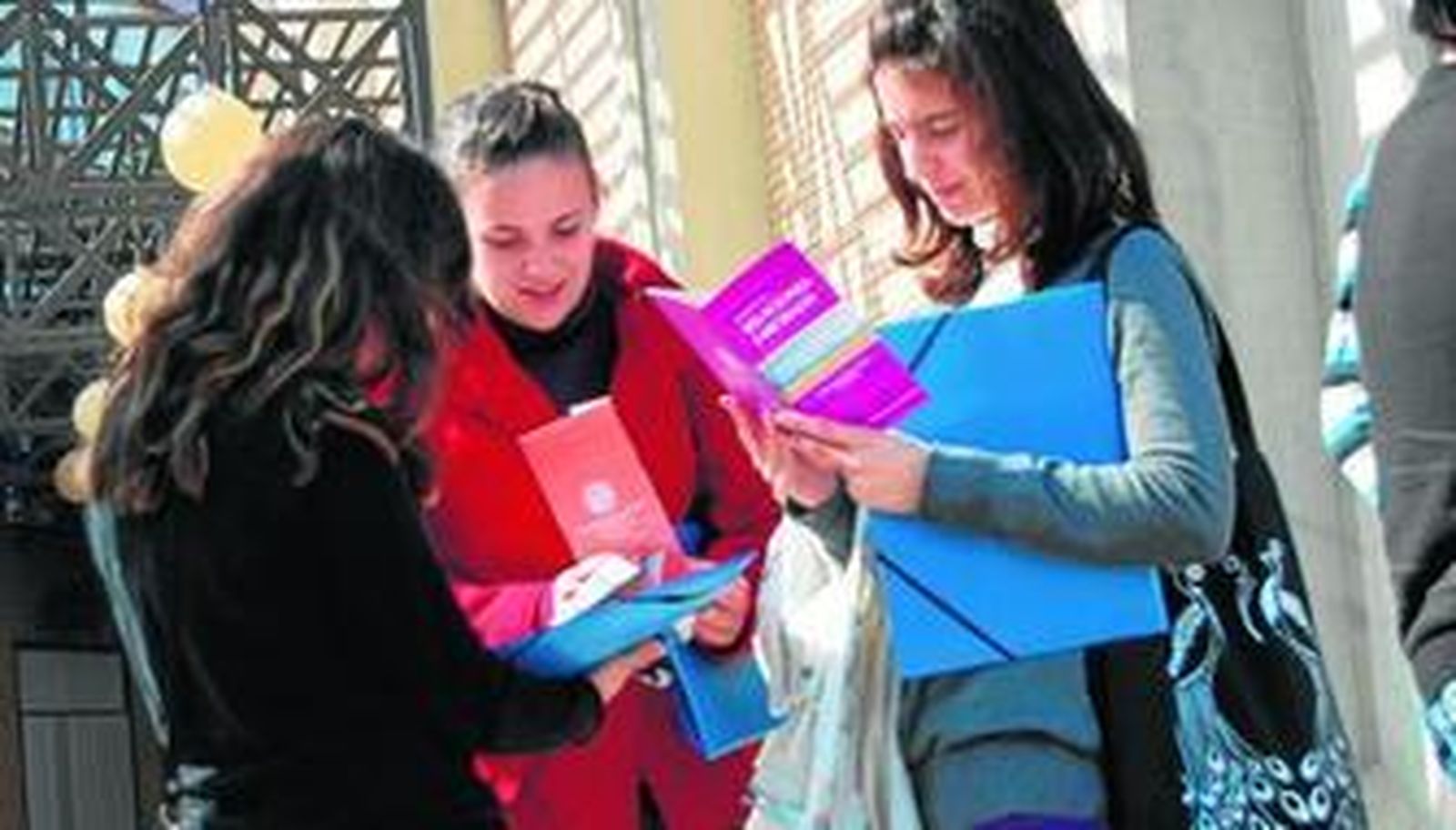 Tres participantes hablan tras las jornadas y observan uno de los folletos informativos que les han entregado.