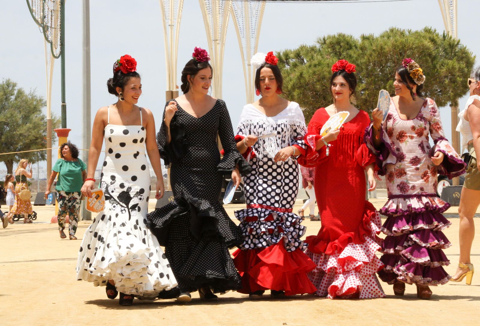 Un grupo de mujeres con trajes de flamenca pasean por el ferial de Las Albinas.