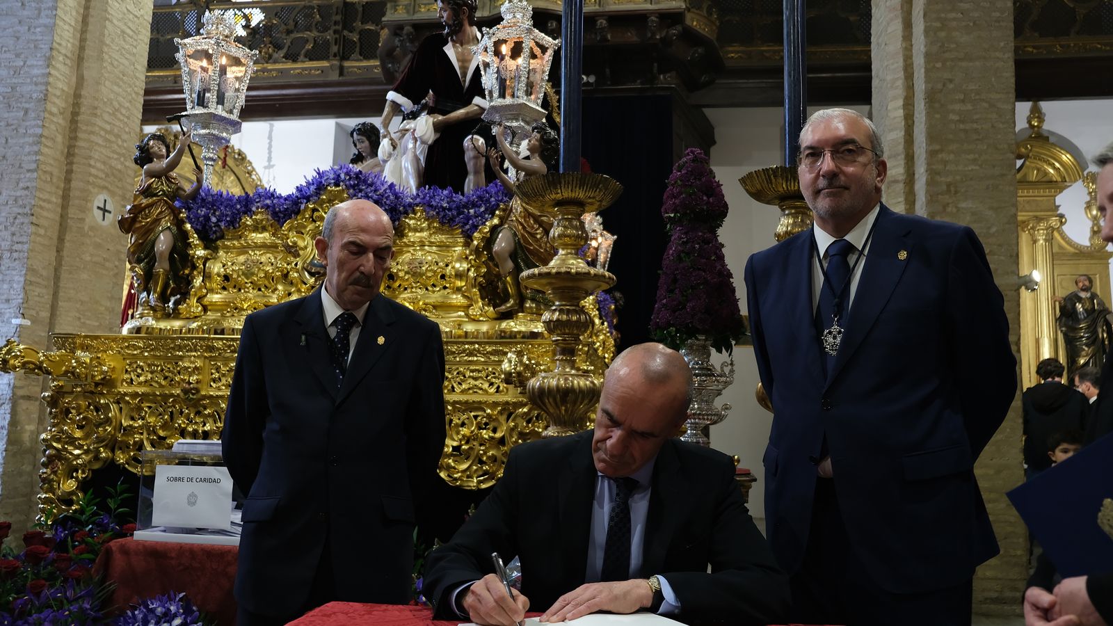 Antonio Muñoz firmando en el libro de honor de Santa Marta junto al teniente hermano mayor y el hermano mayor