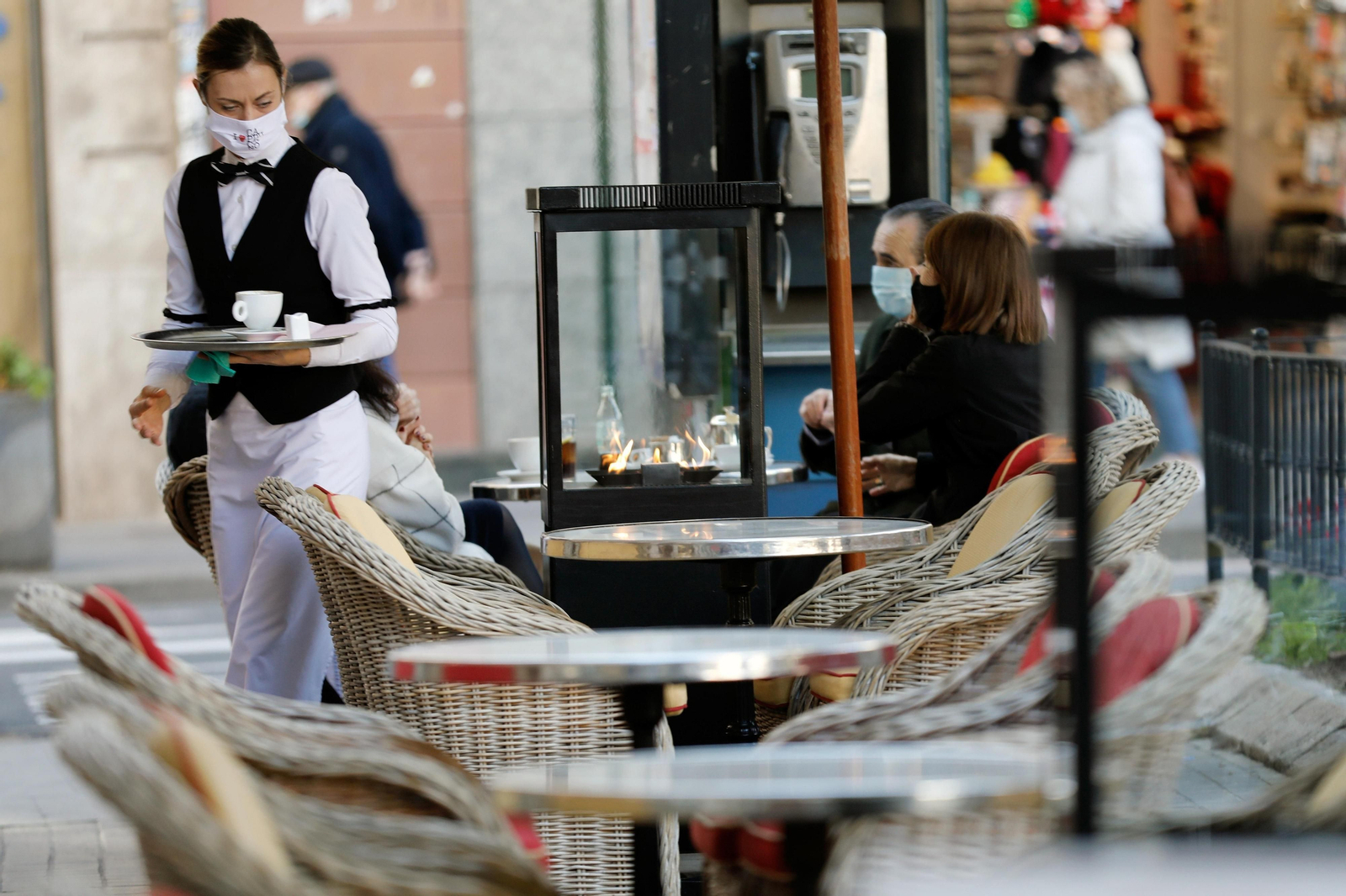 Una camarera atiende a sus clientes en una terraza