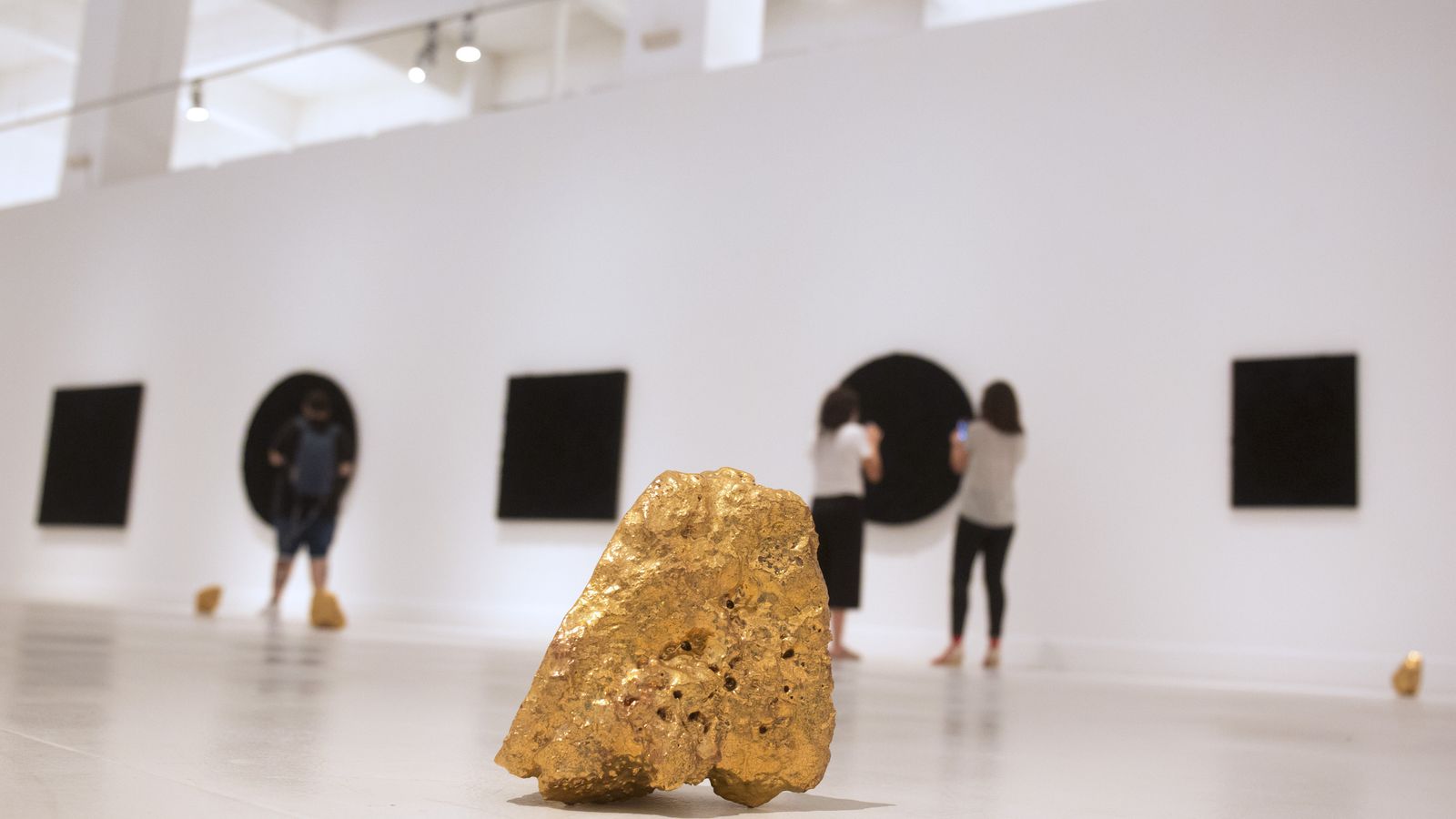Rocas doradas y pinturas geométricas negras, en la exposición.