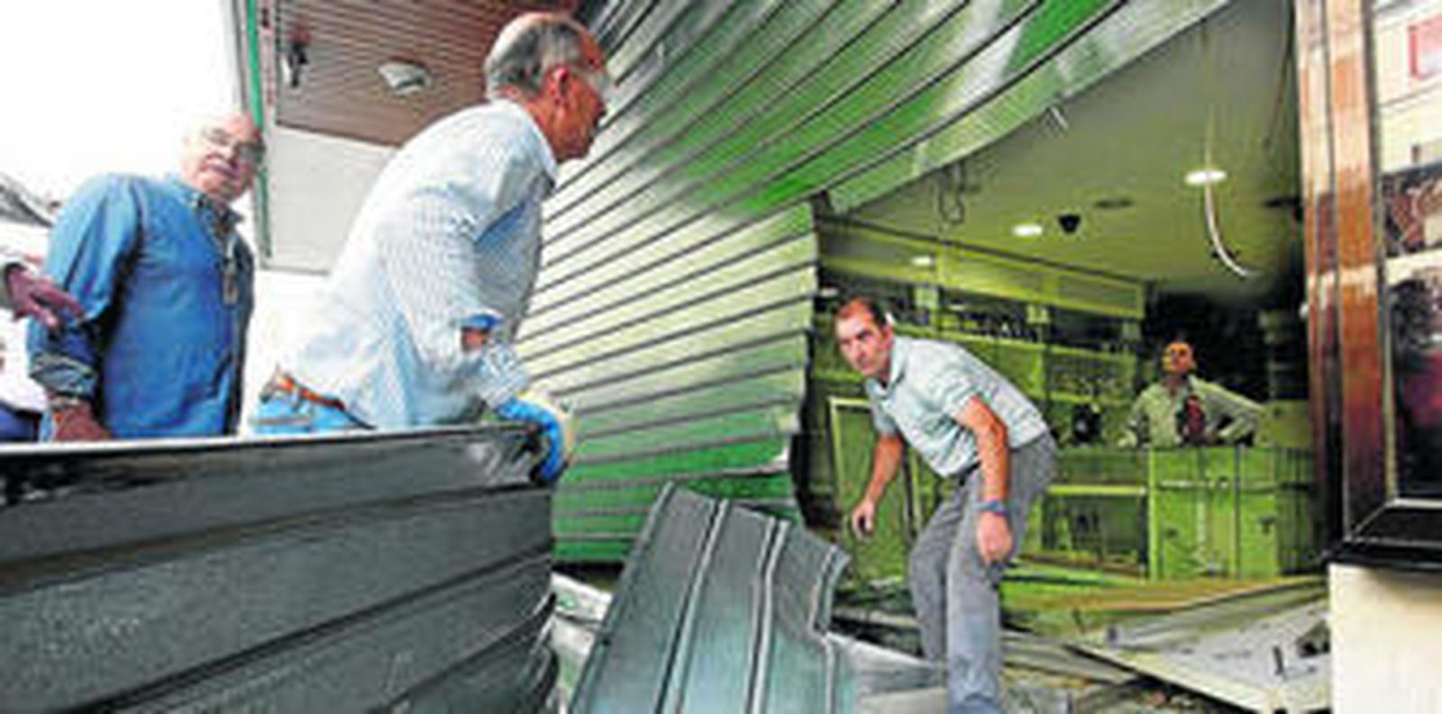 Unos cerrajeros cortan la verja del negocio, ayer, reventada al igual que el escaparate de la joyería.