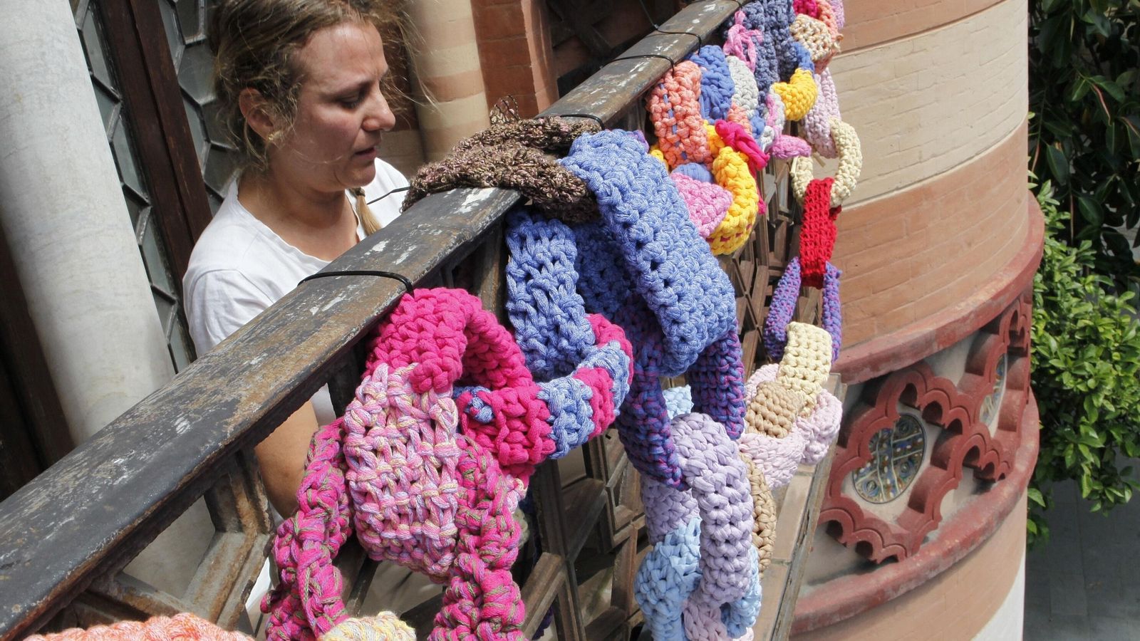 Una de las participantes cuelga del Costurero de la Reina la cadena gigante de ganchillo.
