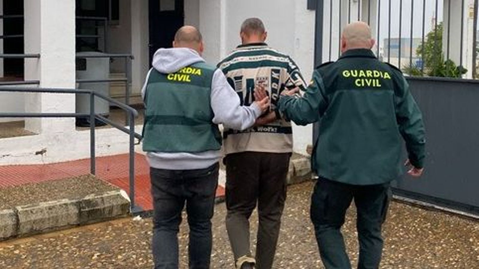 Dos agentes trasladan al ciudadano alemán detenido en El Viso del Alcor.