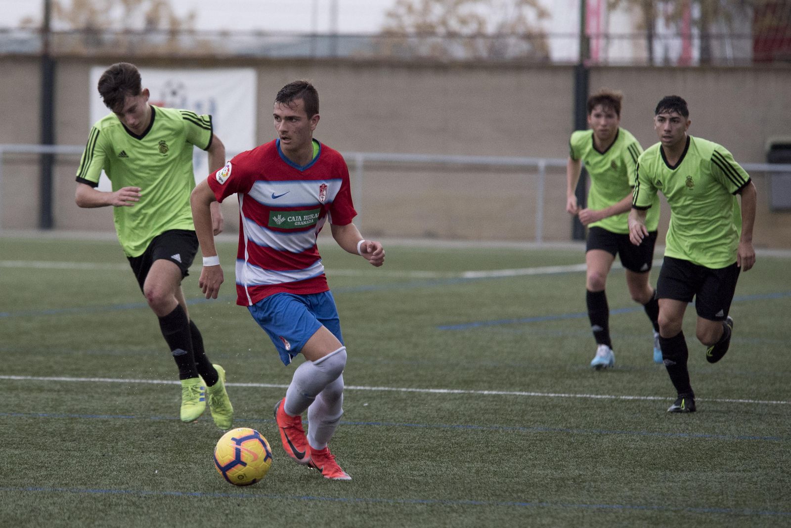 Jugadores del Recreativo juvenil de División de Honor persiguen a un futbolista del Granada.