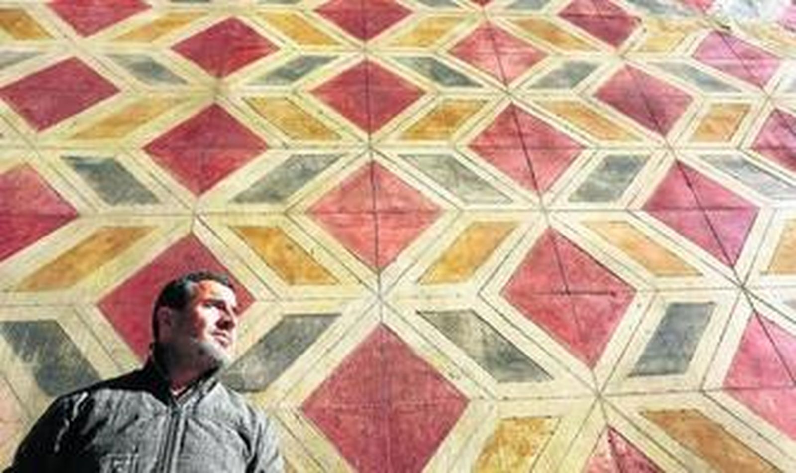 Eduardo Asenjo junto a la fachada de la iglesia de San Juan adornada con pinturas geométricas restauradas en 1999, que ya empiezan a sufrir otra vez el acoso de los años.