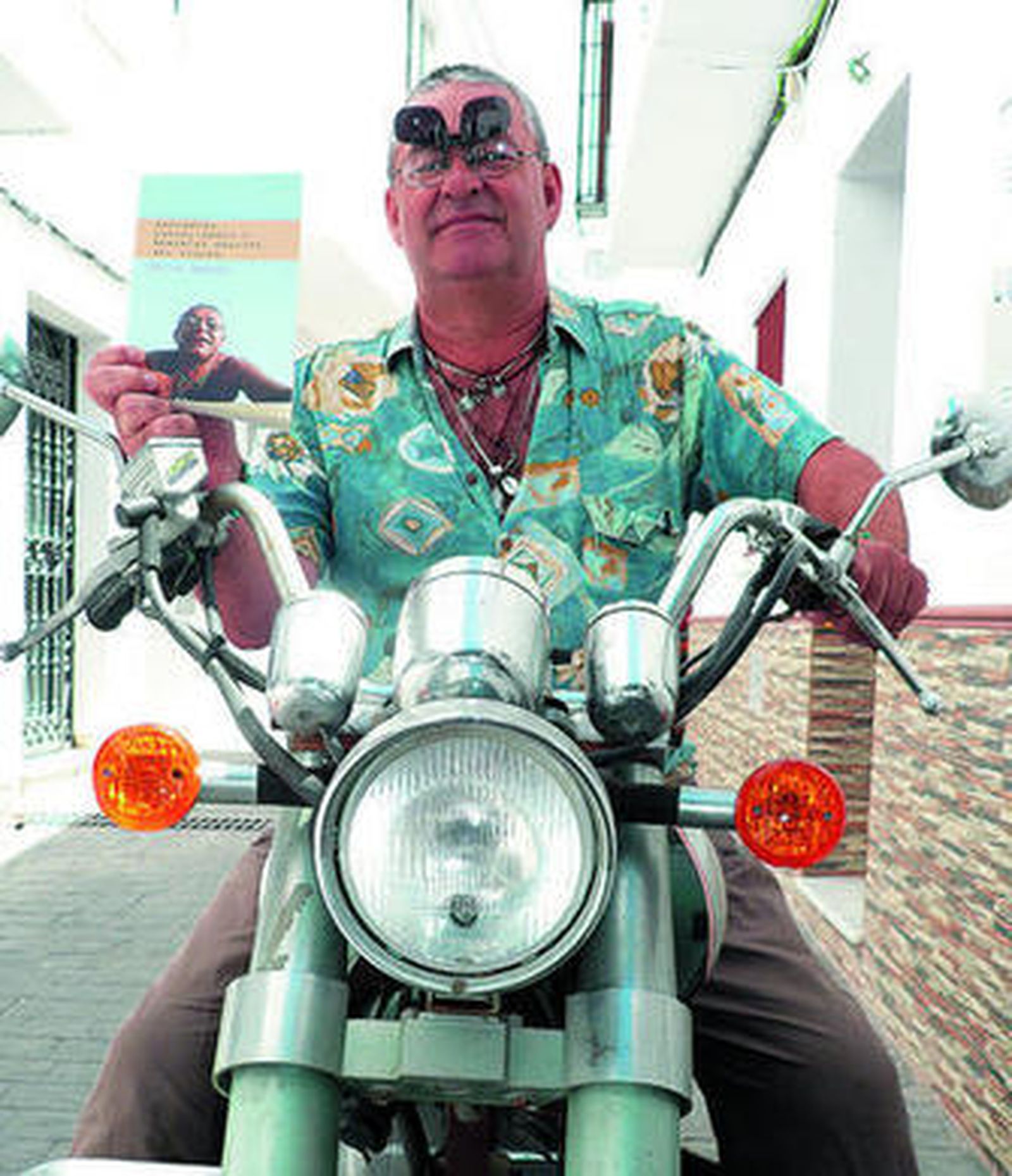 Félix Garcés, con su inseparable moto, muestra un ejemplar de su libro