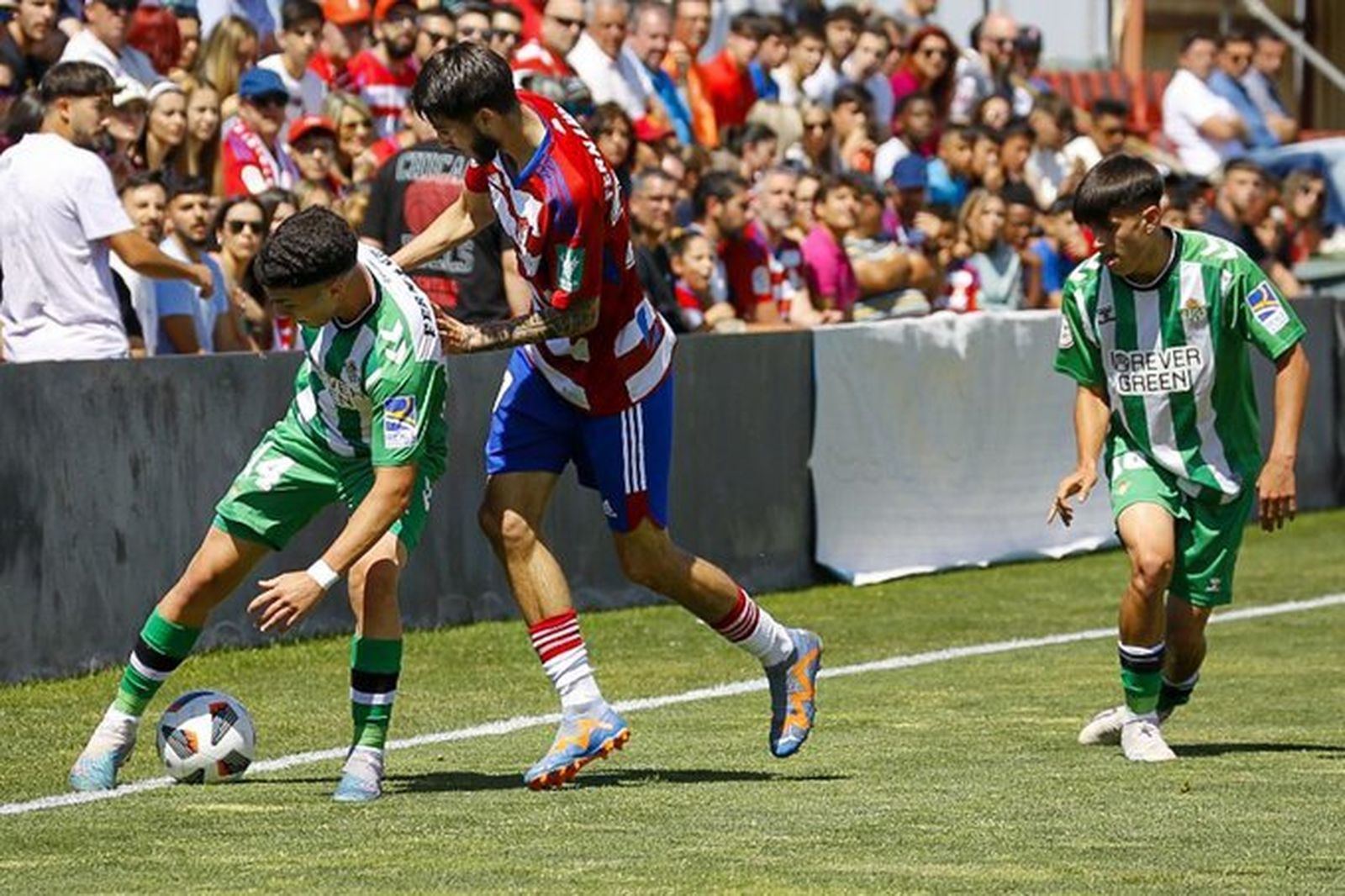 Quique protege el balón ante la presión de un rival granadino.