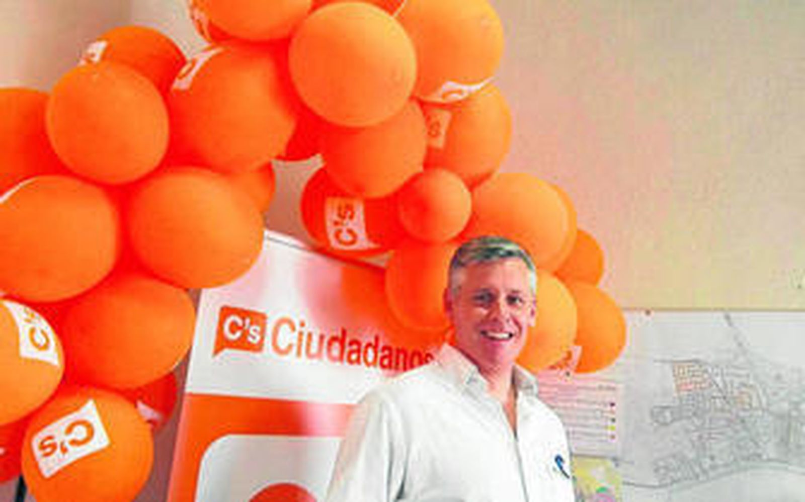 Fotografía que se toma el candidato de Ciudadanos en su sede con el cartel de la formación detrás.