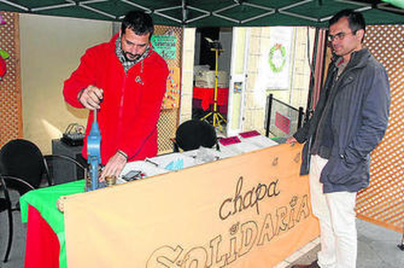 Un joven aguarda mientras manufacturan la chapa solidaria que ha adquirido.