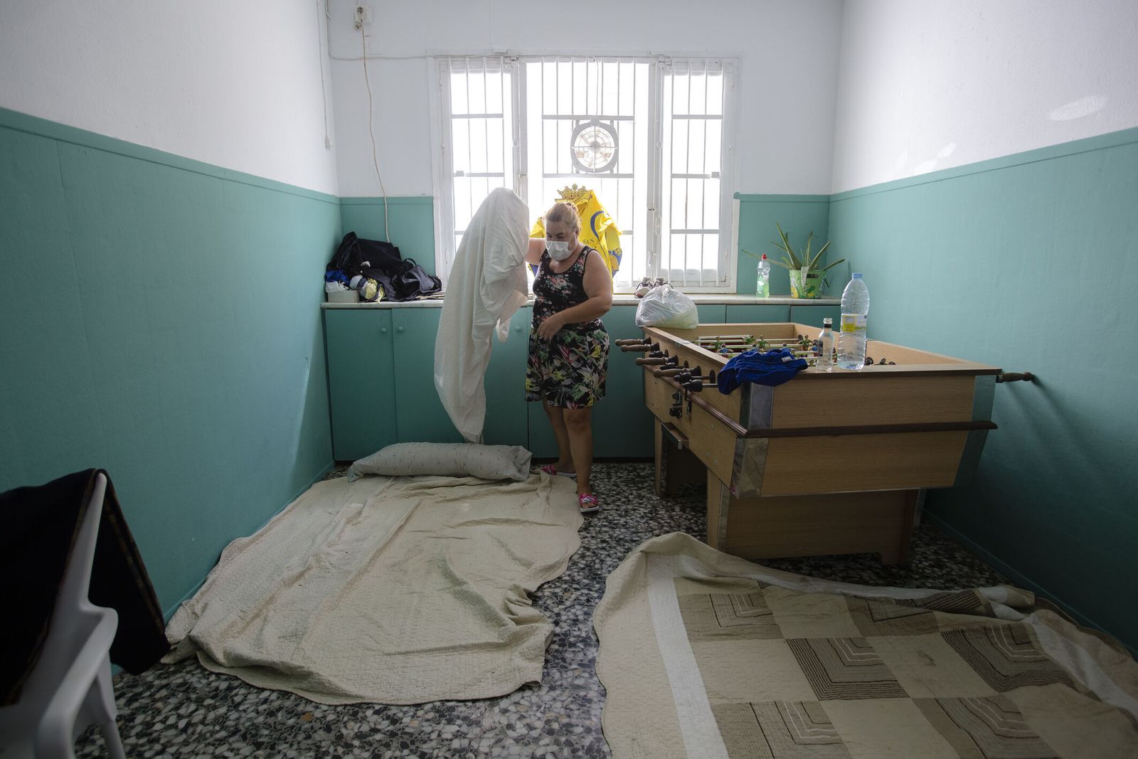 La madre de esta familia recoge las sabanas y la colcha en las que duermen, sin colchón, sobre el suelo del bar.