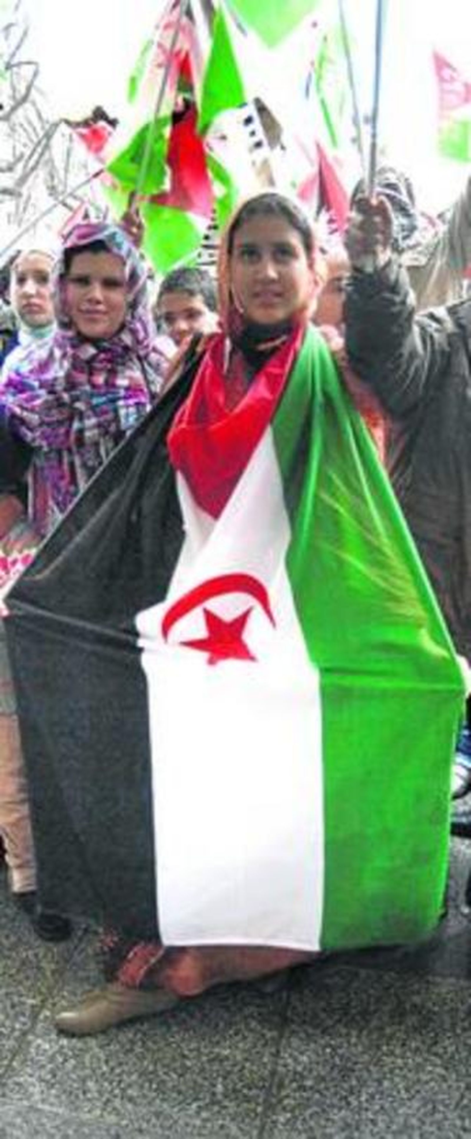 Una asistente a la manifestación, envuelta en la bandera del Sahara.