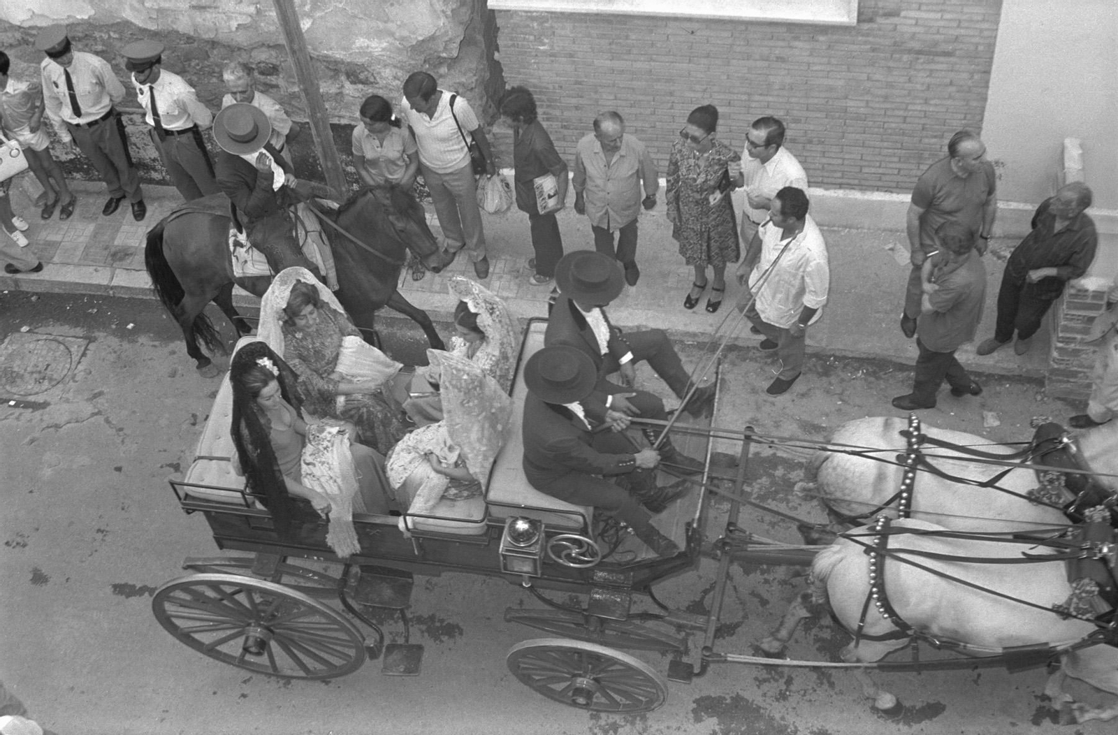 Un grupo de mujeres en mantilla pasean en un coche de caballos
