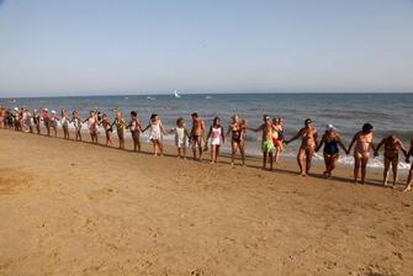 Cadena de los veraneantes, ayer por la tarde, reivindicando información sobre los lodos que afloran en la playa.