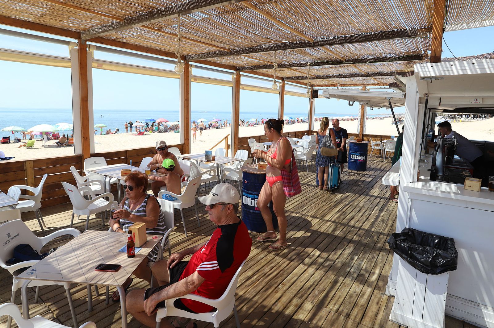 Turistas y visitantes disfrutan de los tesoros de las costa onubense en un chiringuito.