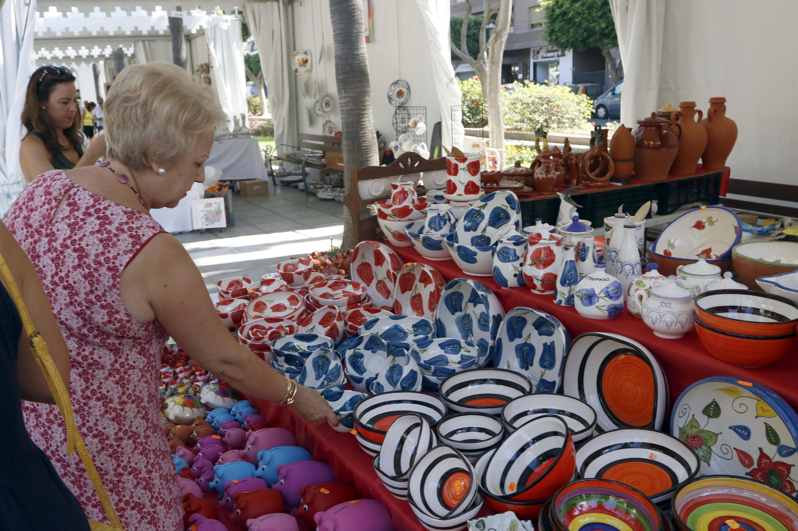 Una mujer observa los fuentes pintadas a mano con flores y listas.